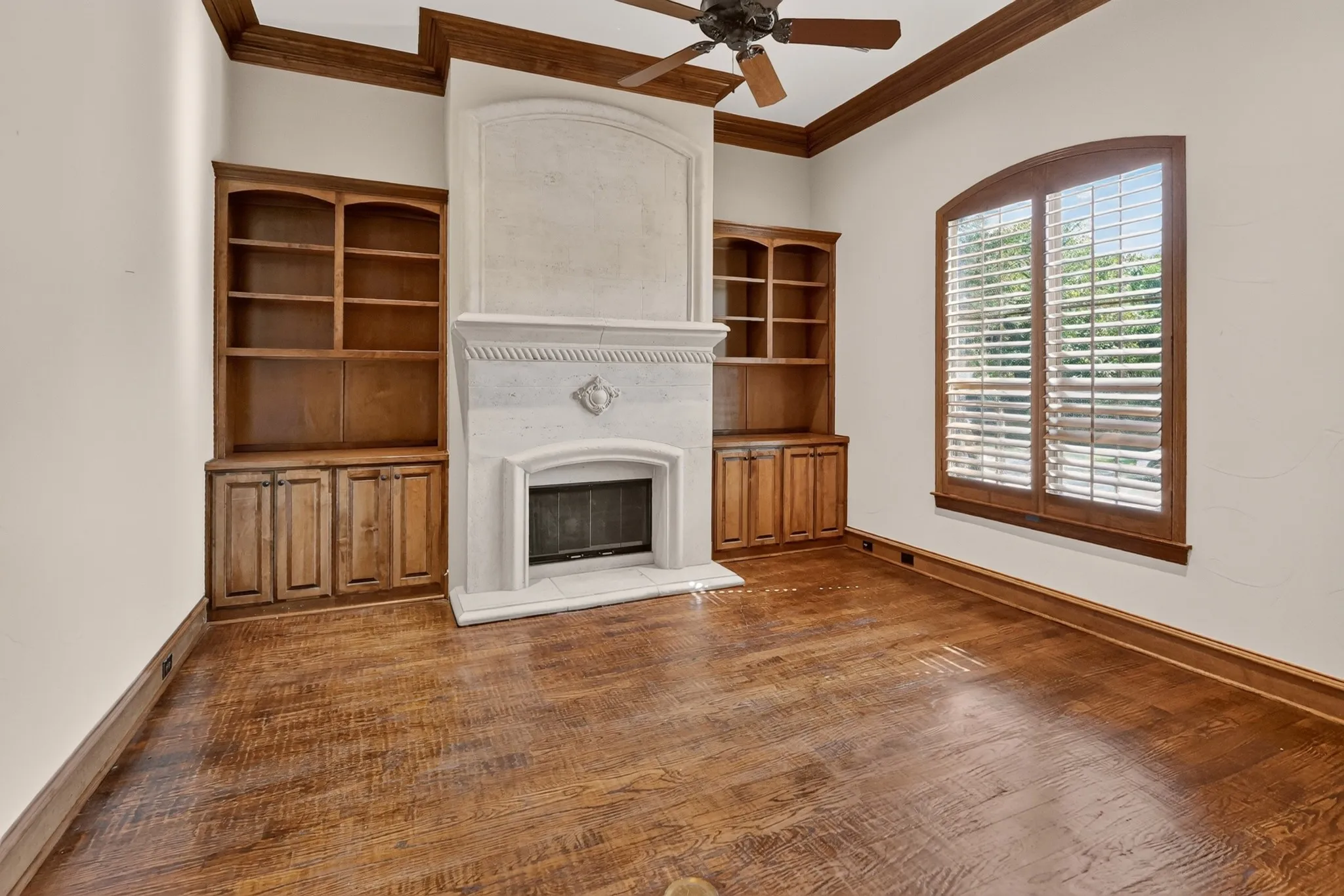 Front formal living or office with stone fireplace with hearth, hand scraped wood flooring, and built-in wooden cabinetry.