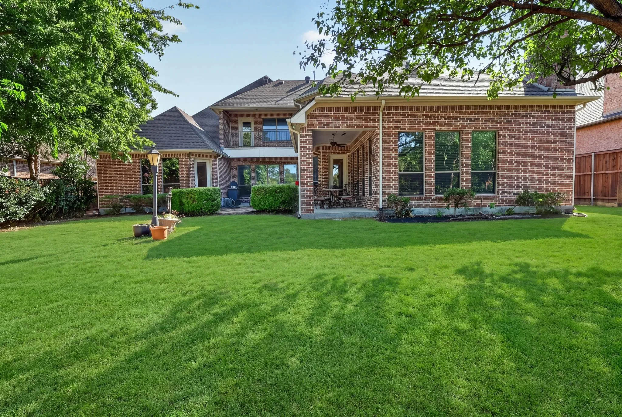 Expansive backyard with water view featuring, brick exterior, covered patio, and mature trees. Virtually Staged