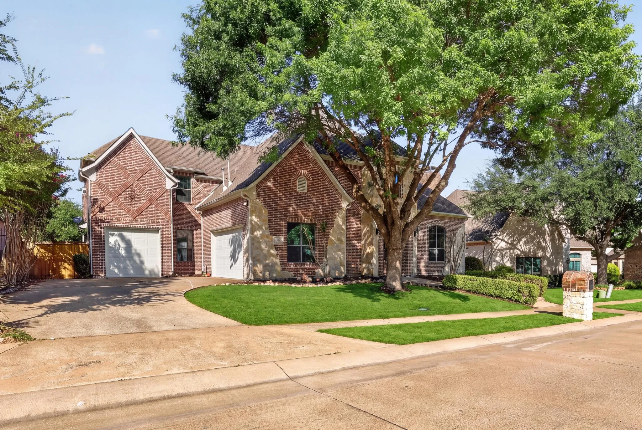 Brick and stone veneer exterior with a three-car garage, mature trees, and a extra long drive-way
