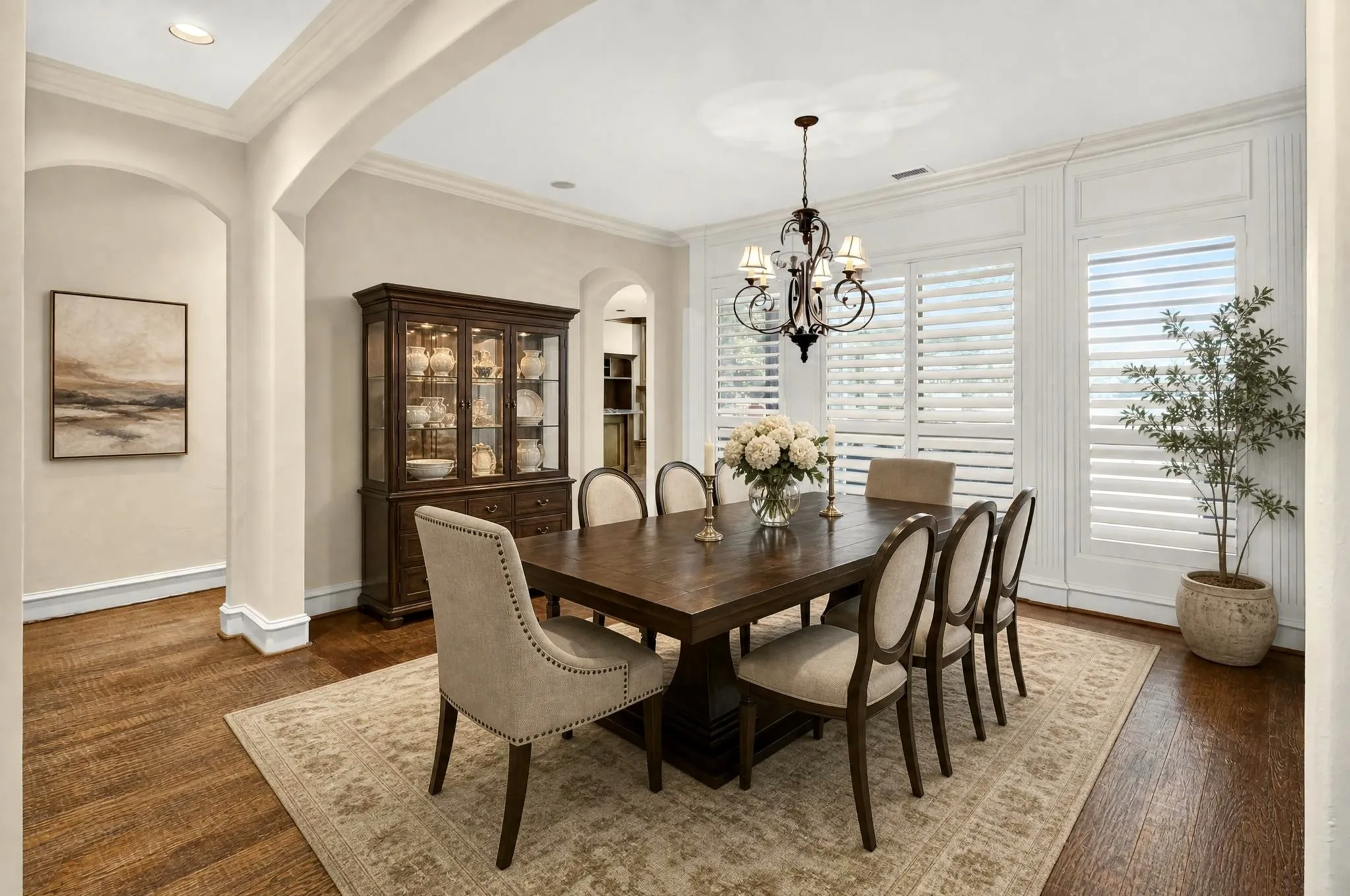 Virtually staged formal dining with archways and wood flooring complement the white paneled walls and plantation shutters. Water View