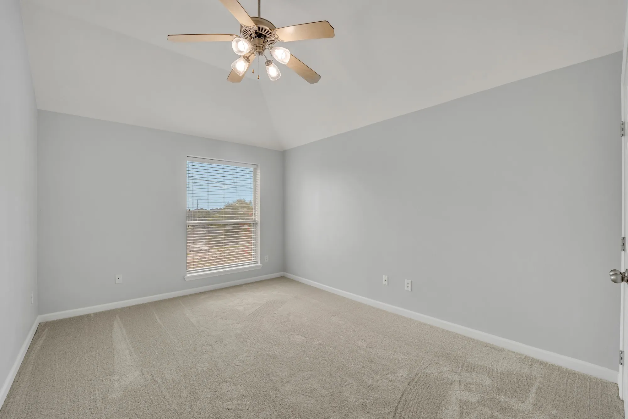 Vaulted ceiling with an attached ceiling fan, neutral wall paint, and carpet flooring