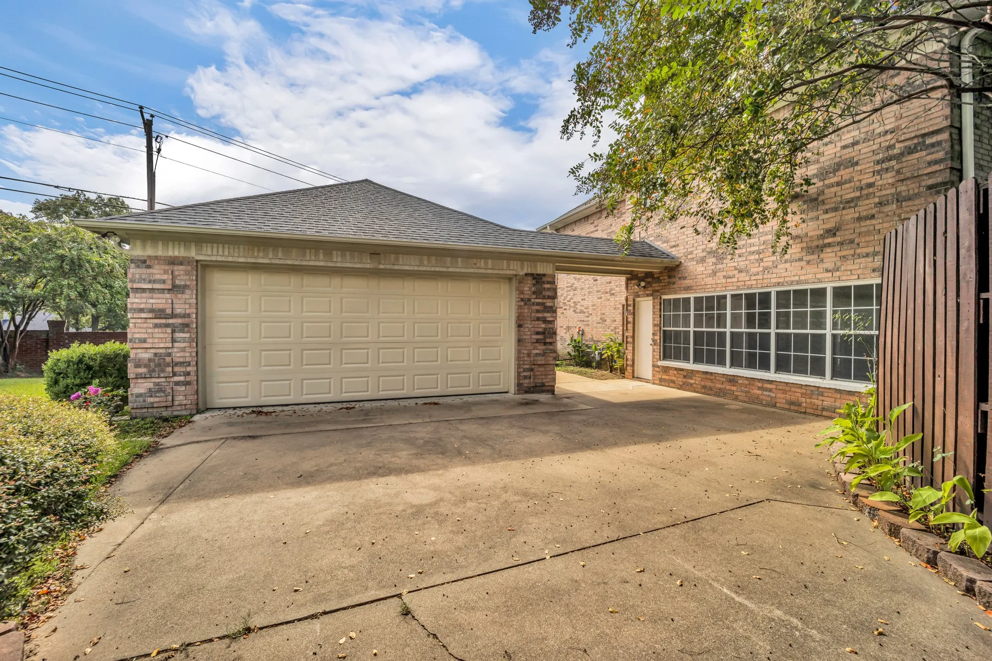 Attached two-car garage with panel door, brick exterior, and concrete driveway
