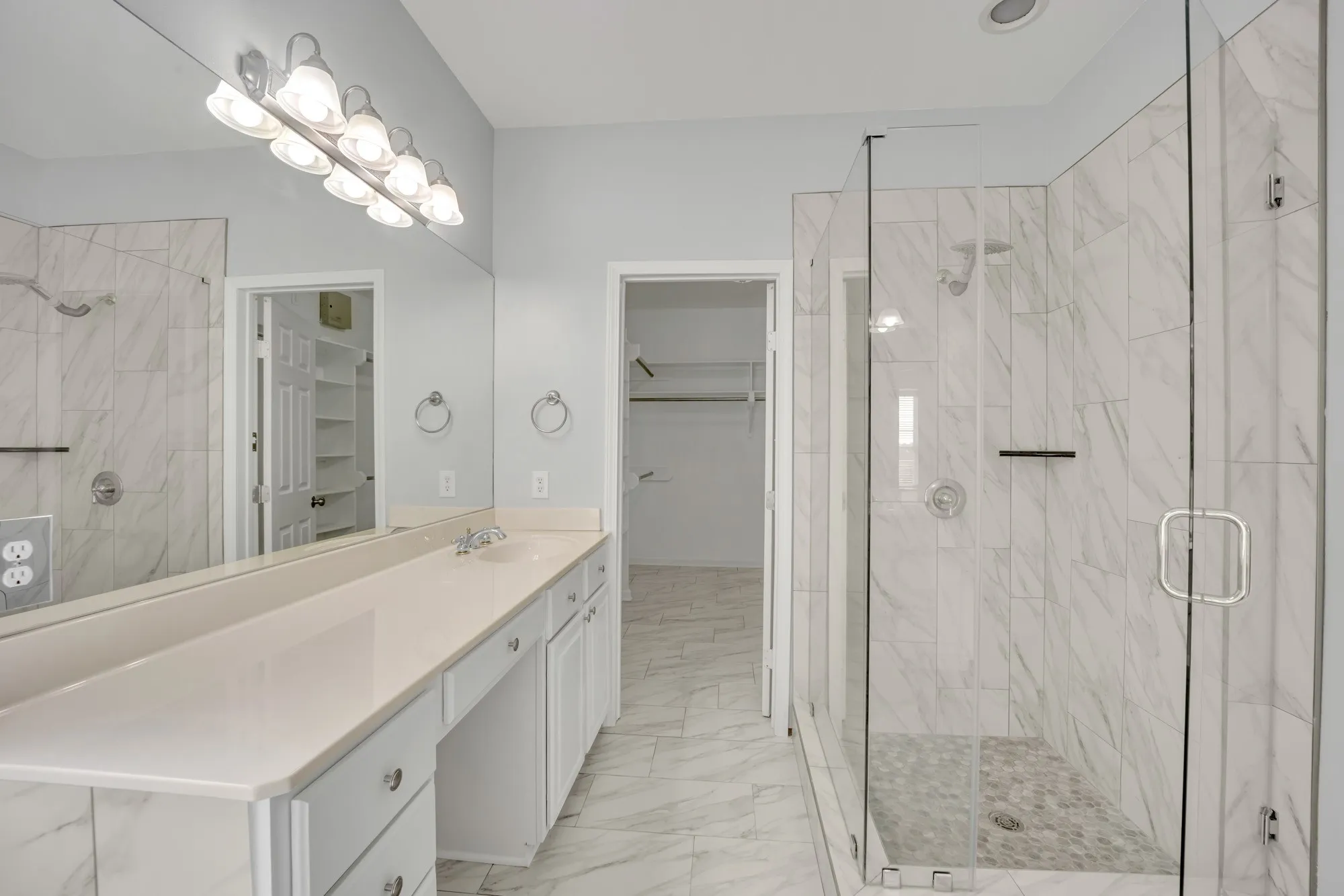 Dual-sink vanity with light-toned countertop, extensive mirror, and built-in cabinetry