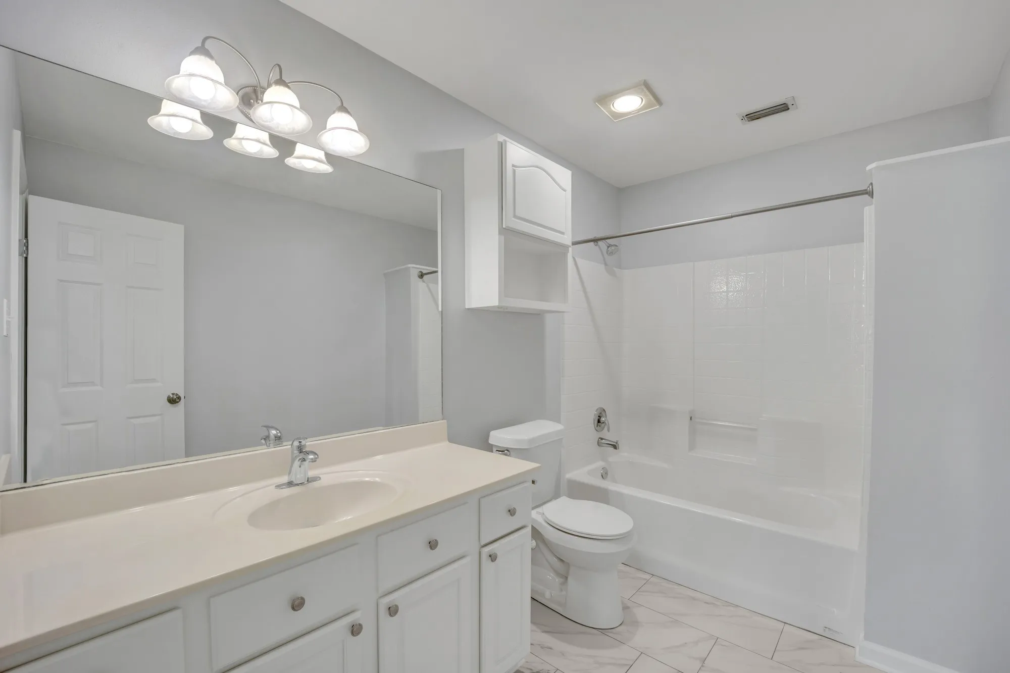 Bathroom featuring a vanity with an integrated sink, a large wall-mounted mirror, a tub/shower combination, and tiled flooring