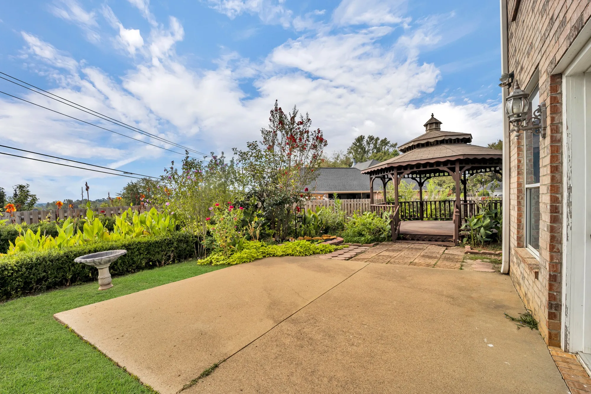 Expansive patio featuring a built-in gazebo, manicured lawn, and mature landscaping