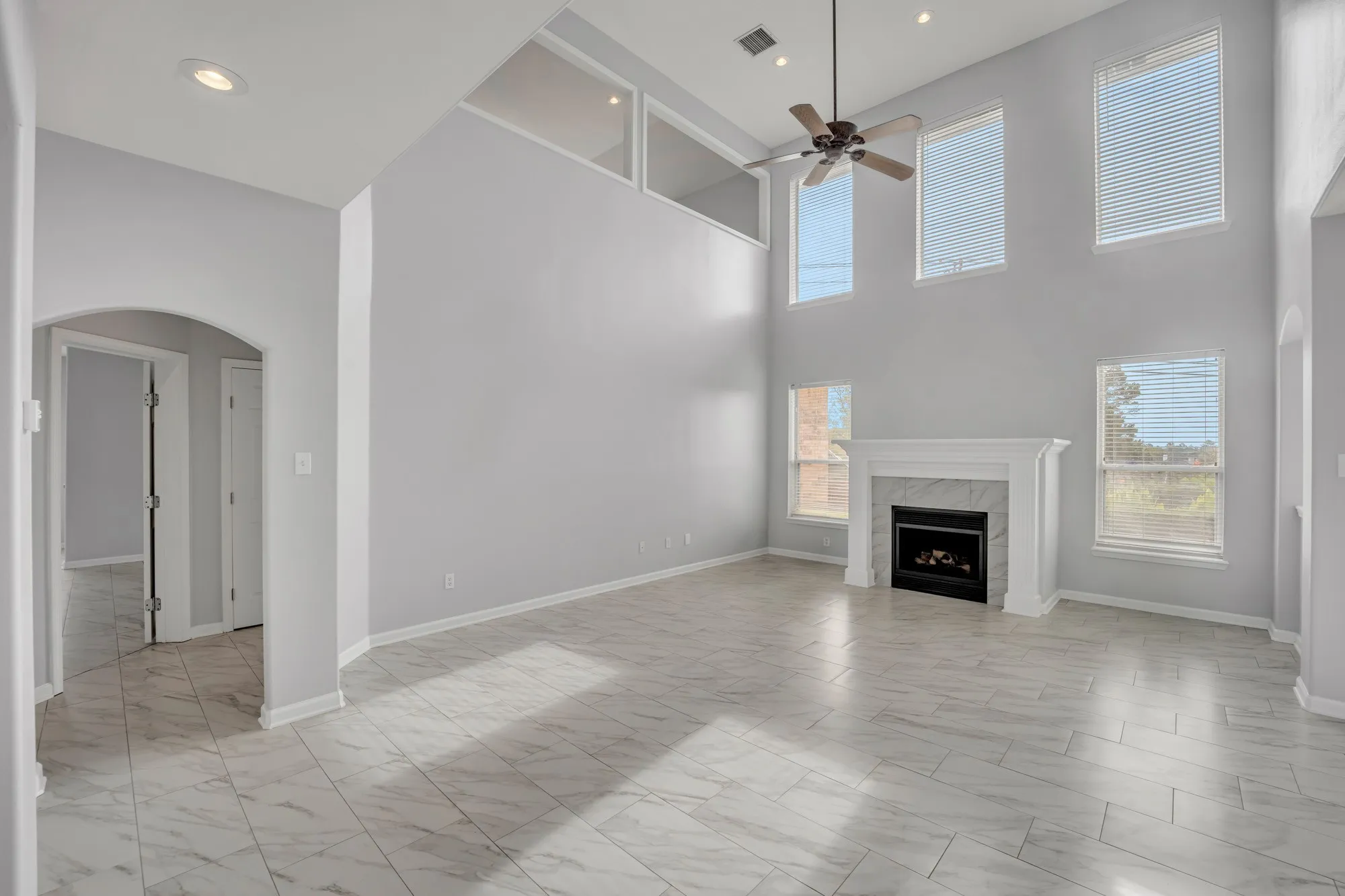 Vaulted ceilings, a built-in fireplace with a stone surround, and multiple windows with blinds