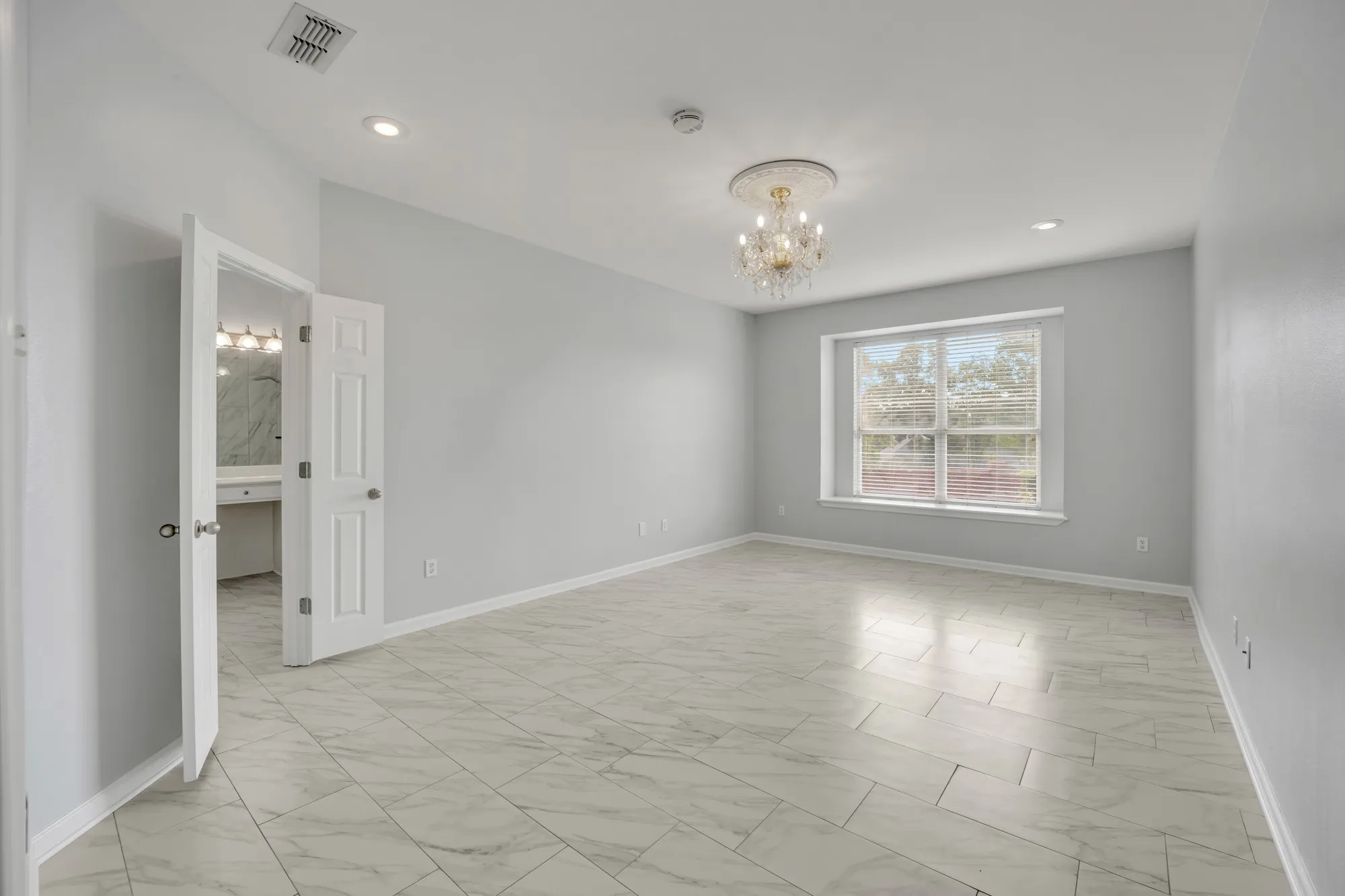 Spacious room featuring large format tile flooring, recessed lighting, and a decorative chandelier