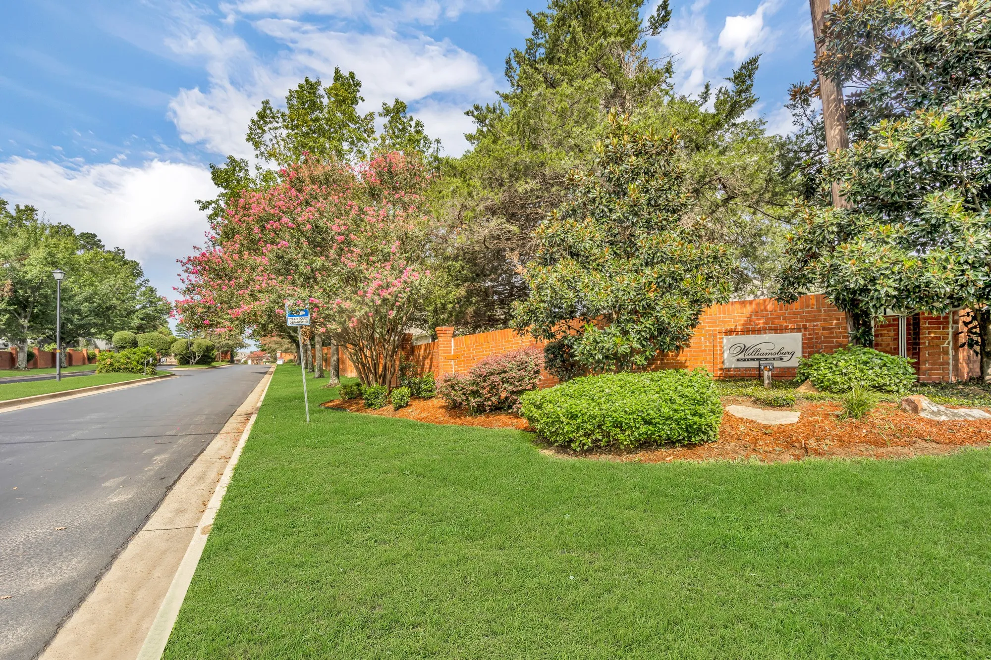 Manicured landscaping with mature trees and a brick wall