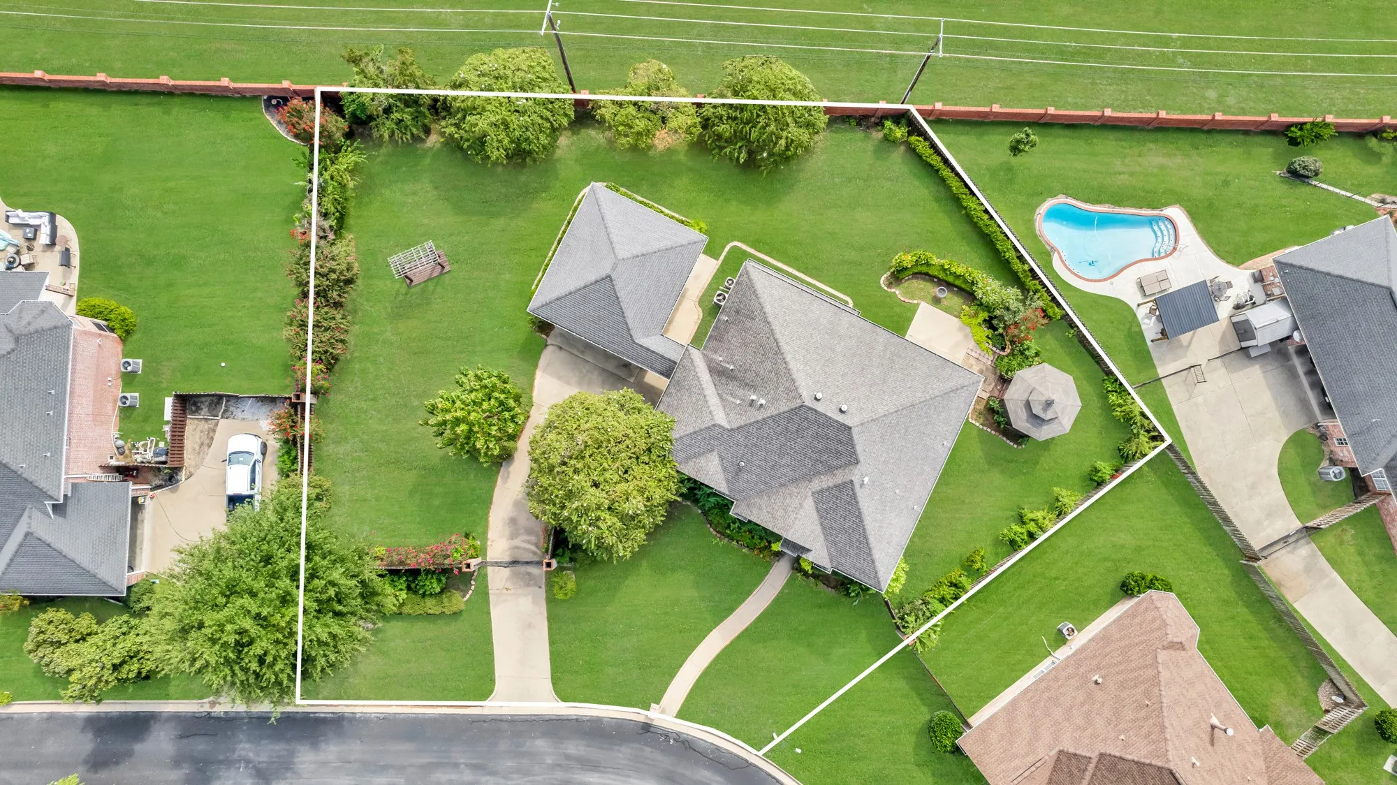 Expansive lot featuring a detached garage, circular driveway, established landscaping, and a gazebo