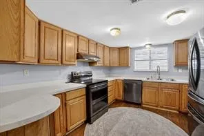 Kitchen featuring wood-finish cabinetry, white countertops, a stainless steel oven/range with an overhead hood, and a stainless steel dishwasher