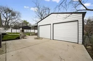 Two-car garage with white paneled doors, concrete driveway, white horizontal siding, and dark trim