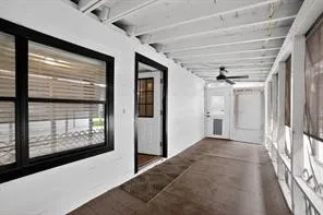 Enclosed porch featuring a ceiling fan, exposed wood beam ceiling, and a dark finished floor