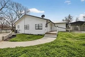 White siding exterior with black-framed windows, a covered entryway, and a concrete pathway
