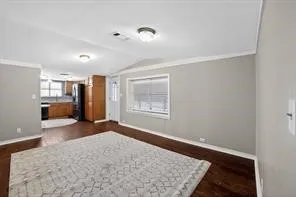 Spacious living area with wood-finish flooring, neutral wall tones, and white trim