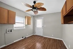 Wood-finish flooring with light gray wall paint, a ceiling fan, and built-in cabinetry