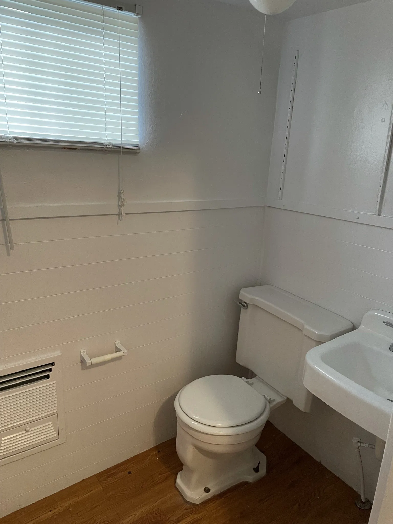 Half bathroom with dark wood-style flooring, a wainscoted wall, and tile walls