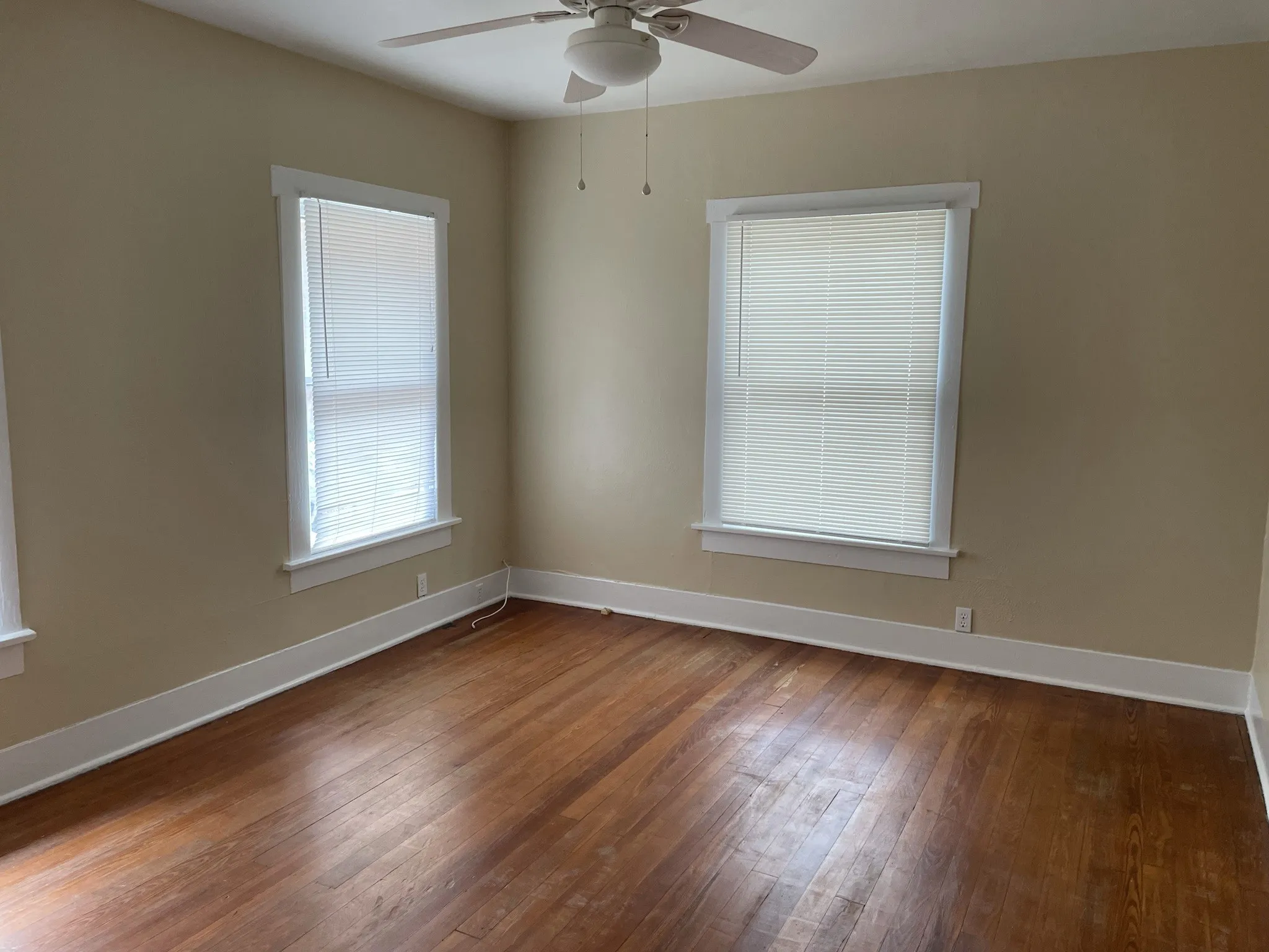 Spare room featuring dark wood-type flooring and ceiling fan