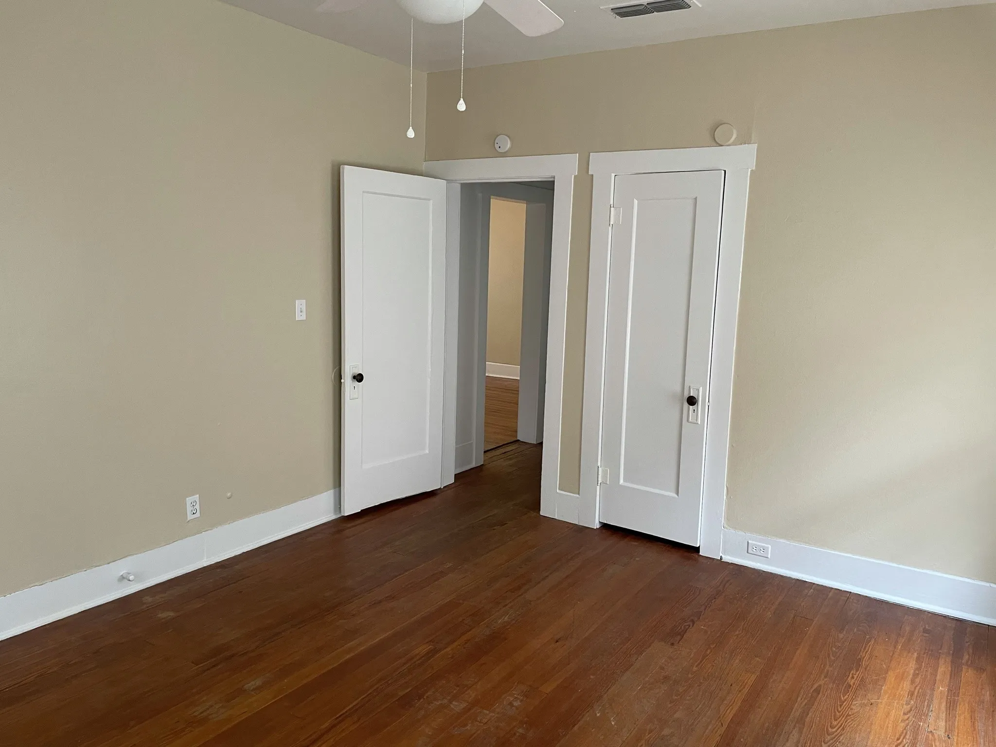 Unfurnished bedroom with dark wood-style floors and ceiling fan