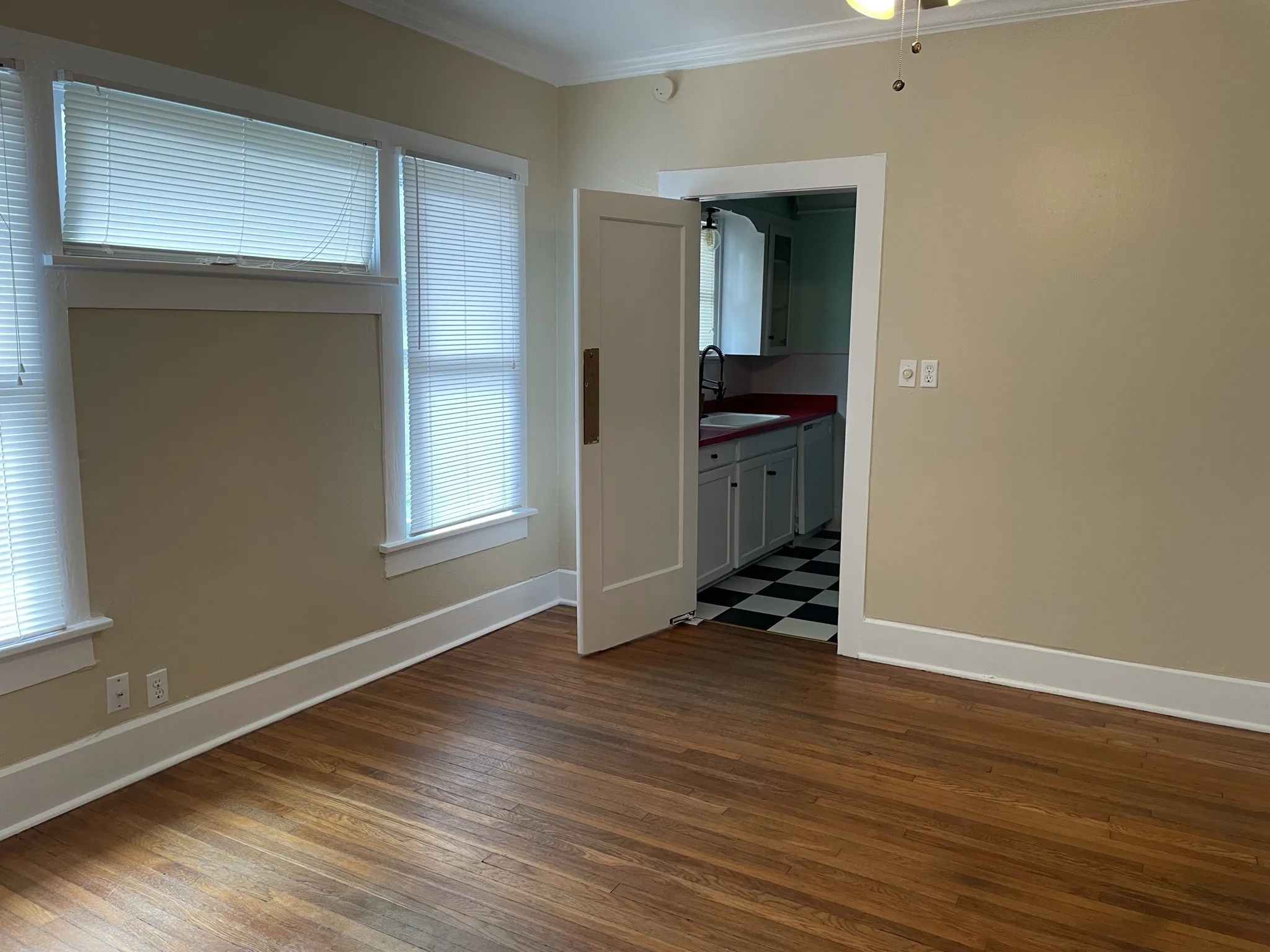 Spare room featuring dark wood-type flooring, ornamental molding, and plenty of natural light