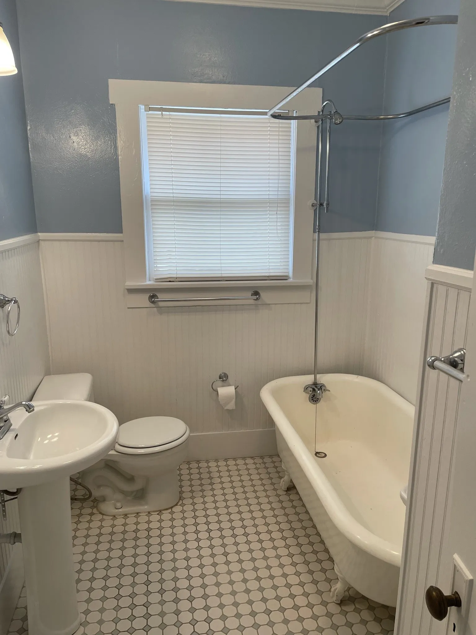 Bathroom with a combined bath / shower with freestanding tub and a wainscoted wall