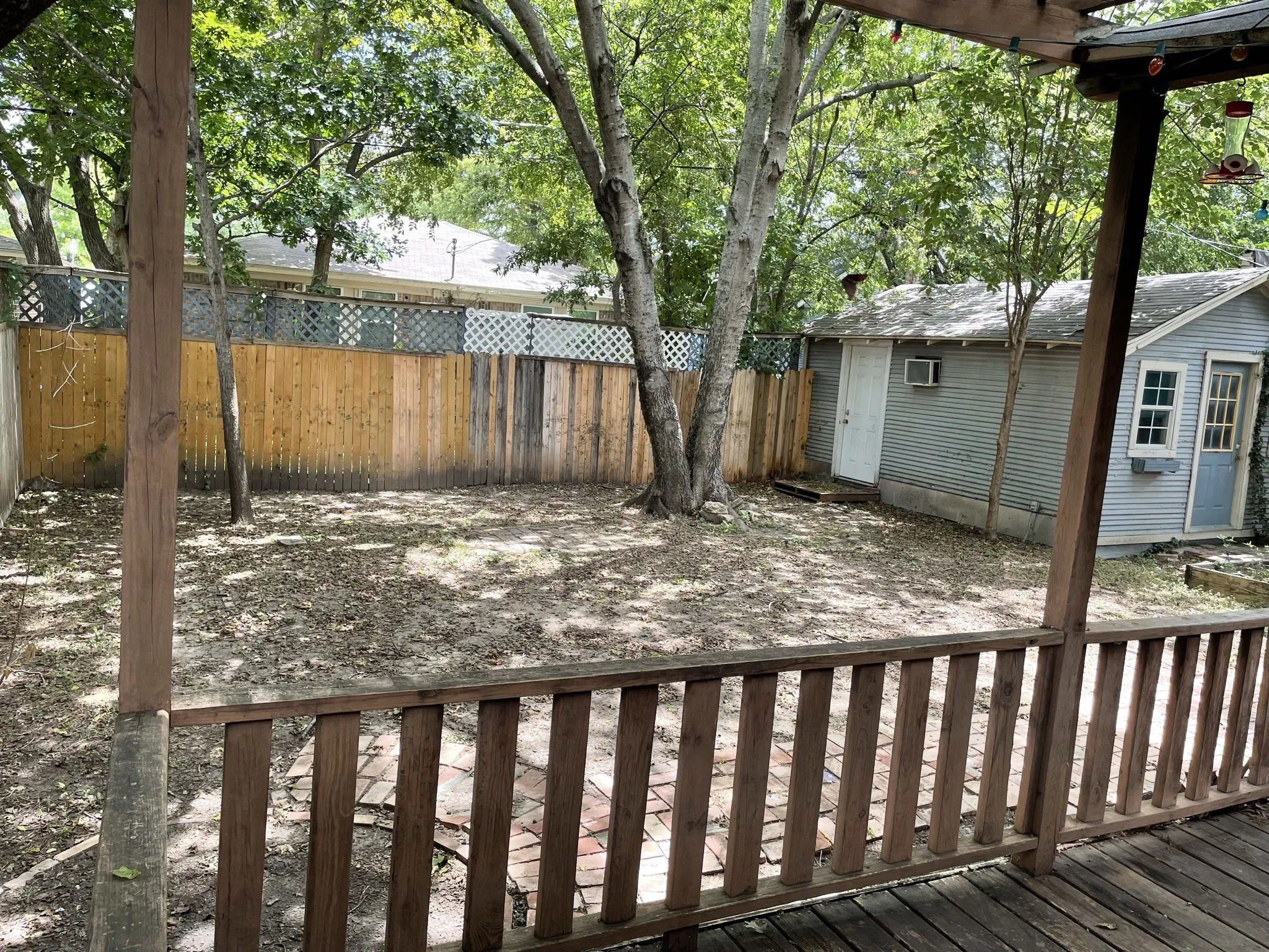 Fenced backyard with a wooden deck and a wall mounted AC