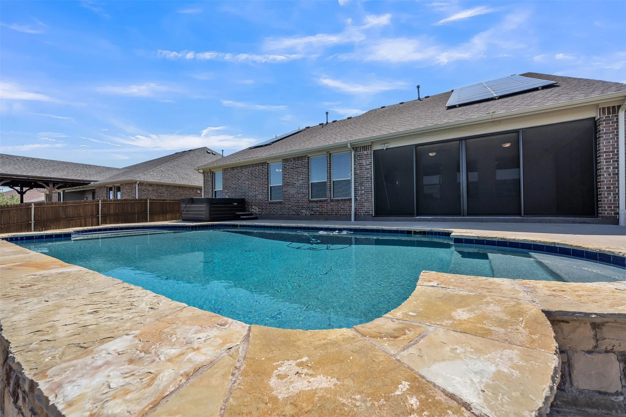 Private backyard with a rectangular pool, flagstone coping, and a built-in spa
