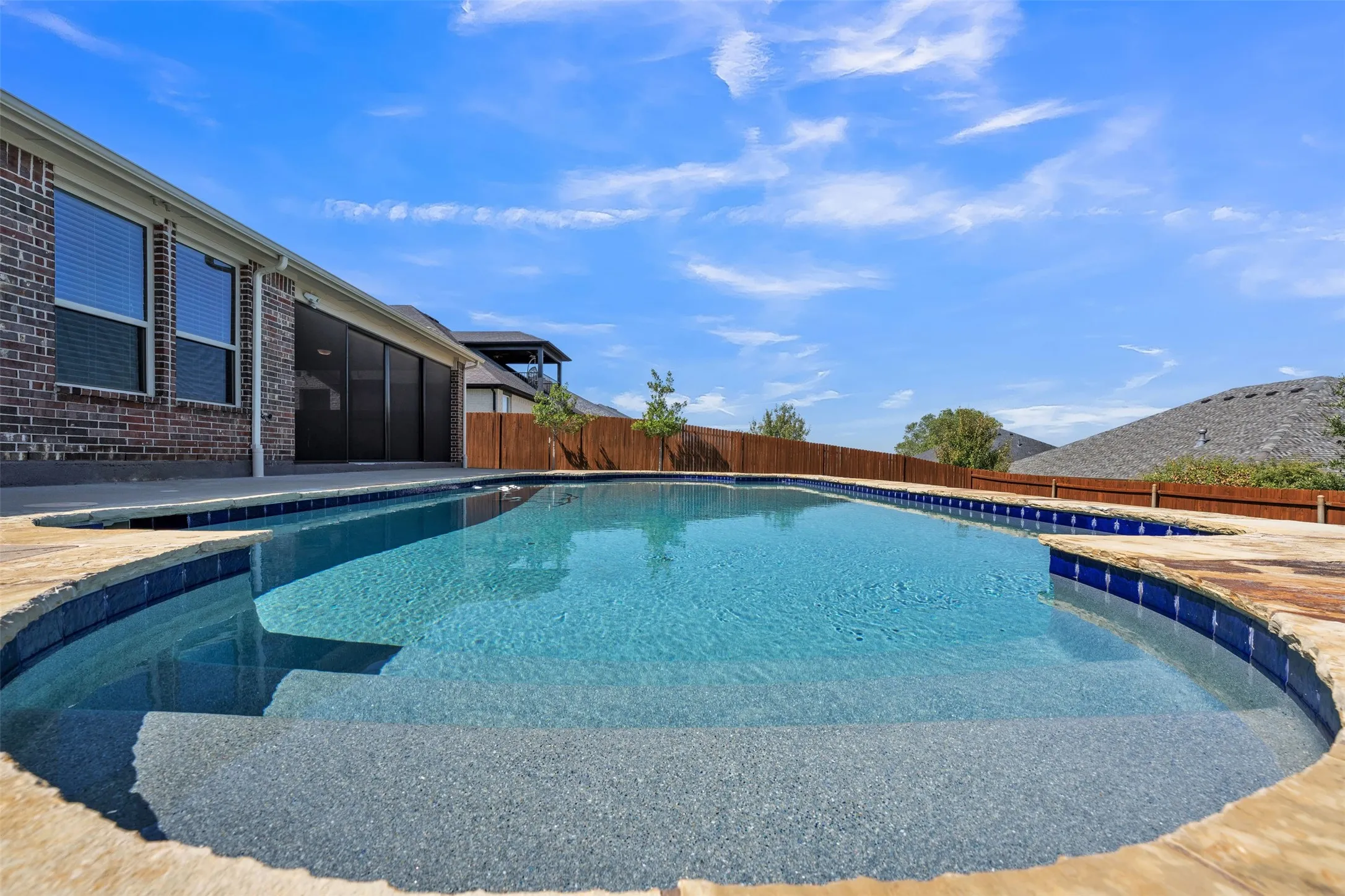 In-ground swimming pool with integrated steps, adjacent hot tub, and stone coping