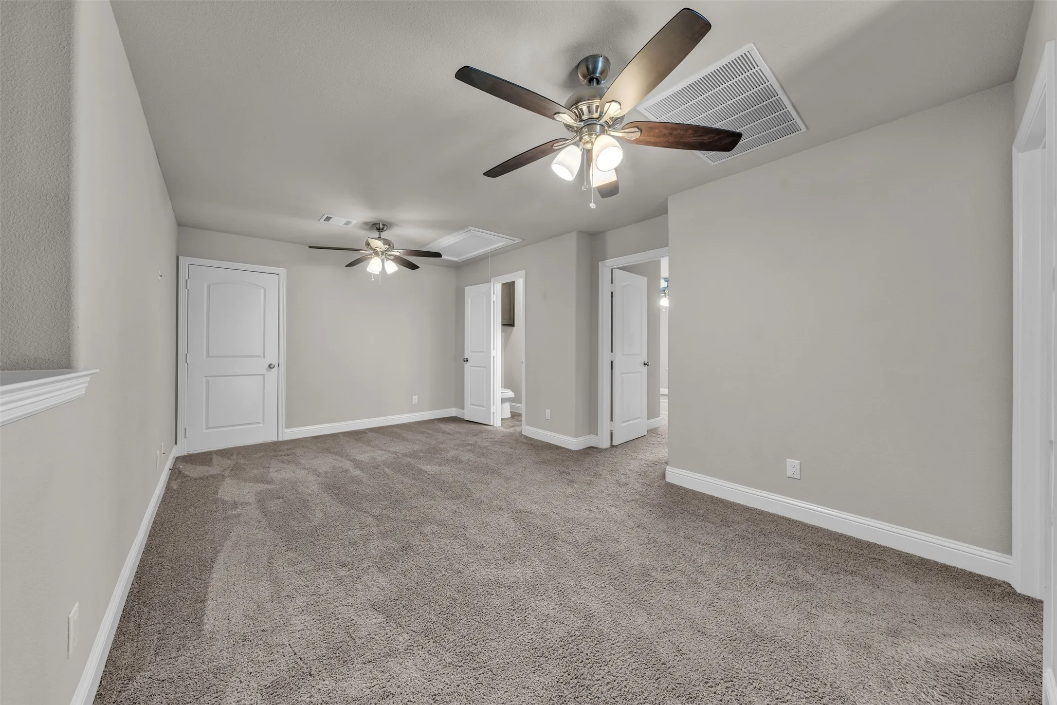 Spacious room with gray textured carpeting, neutral wall paint, and white trim