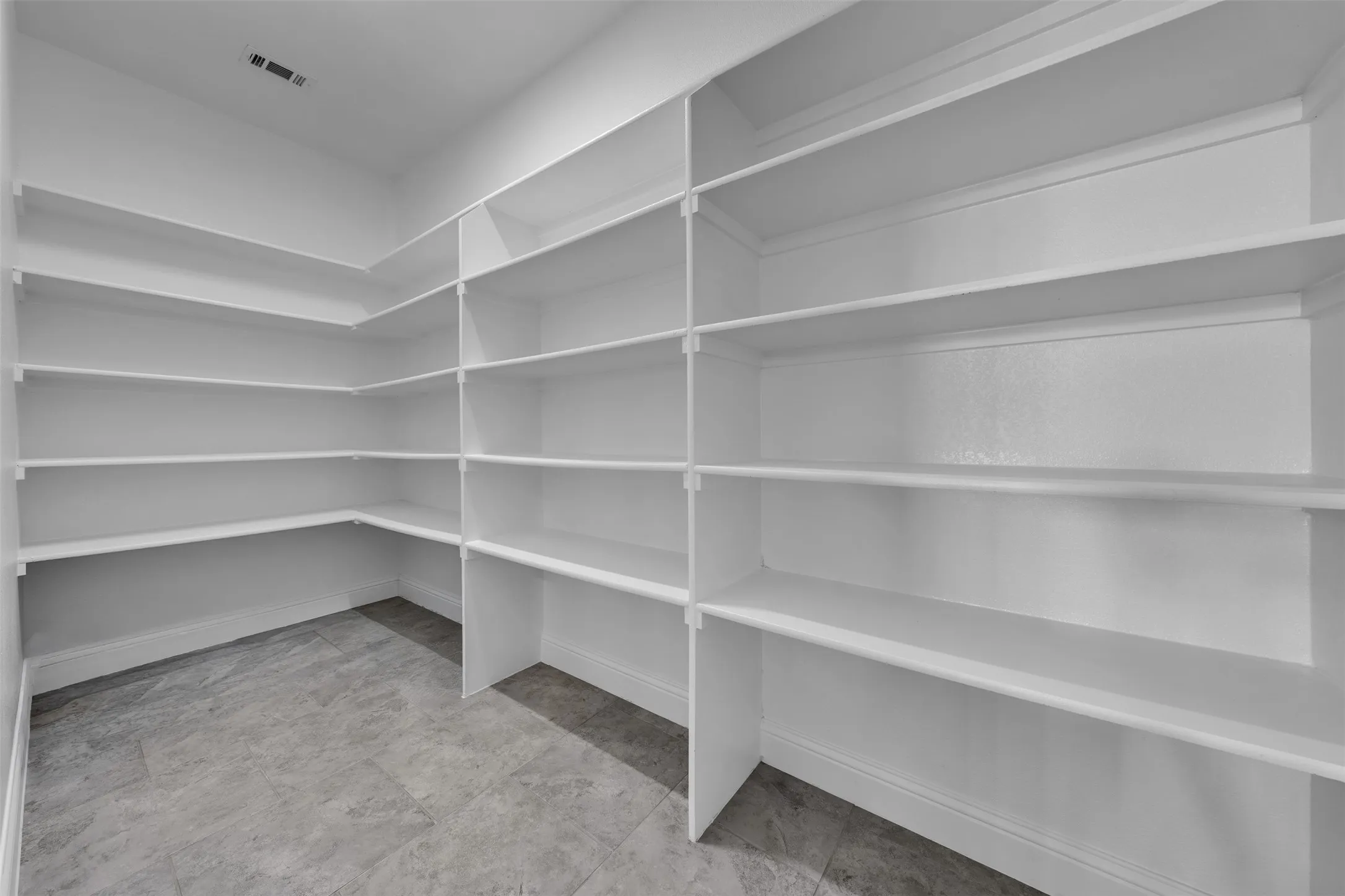 Extensive built-in shelving with crown molding, durable tile flooring, and clean white finishes