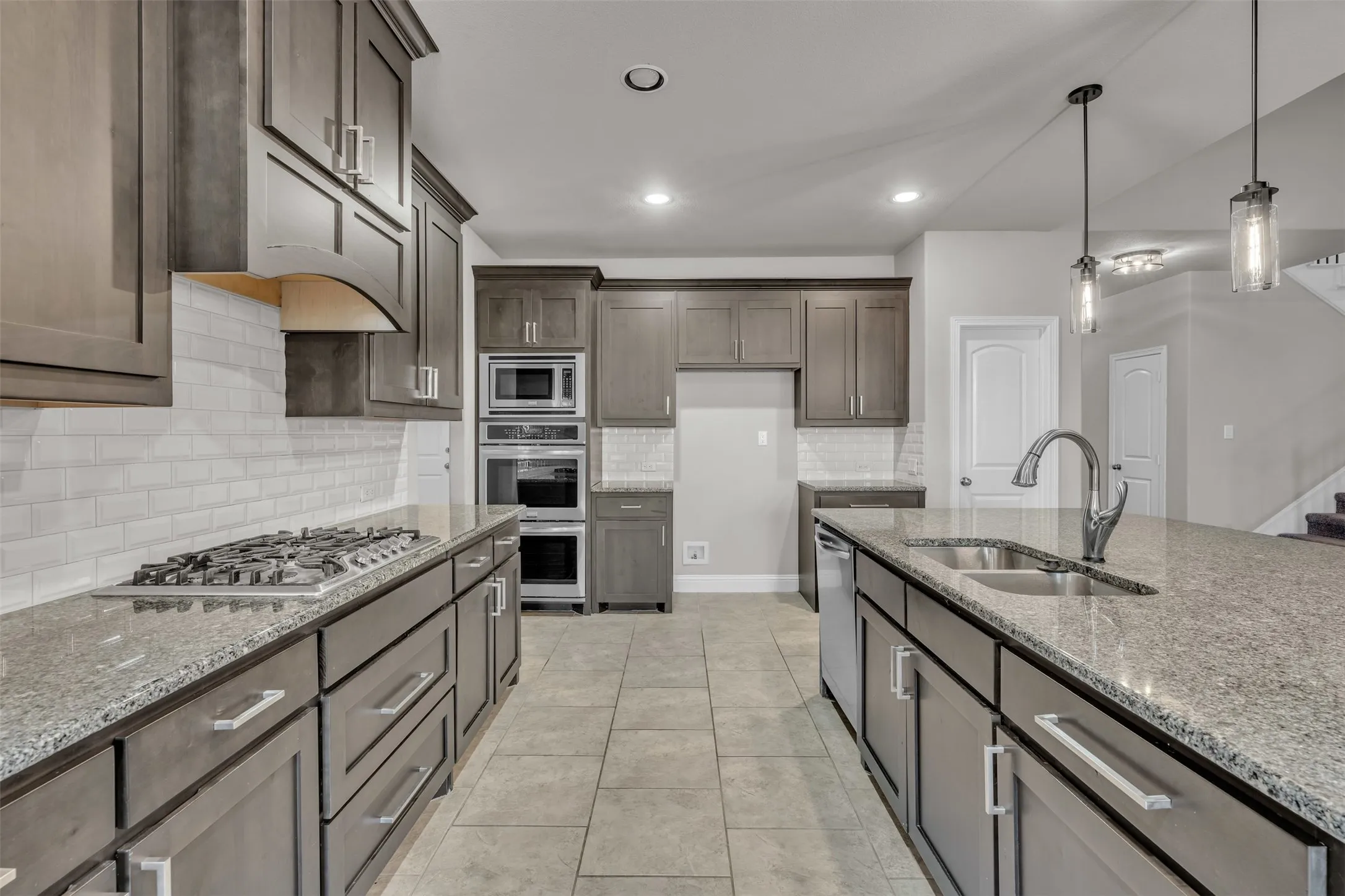Gourmet kitchen featuring gray cabinetry, stainless steel appliances, a gas cooktop, and a kitchen island with dual pendant lighting