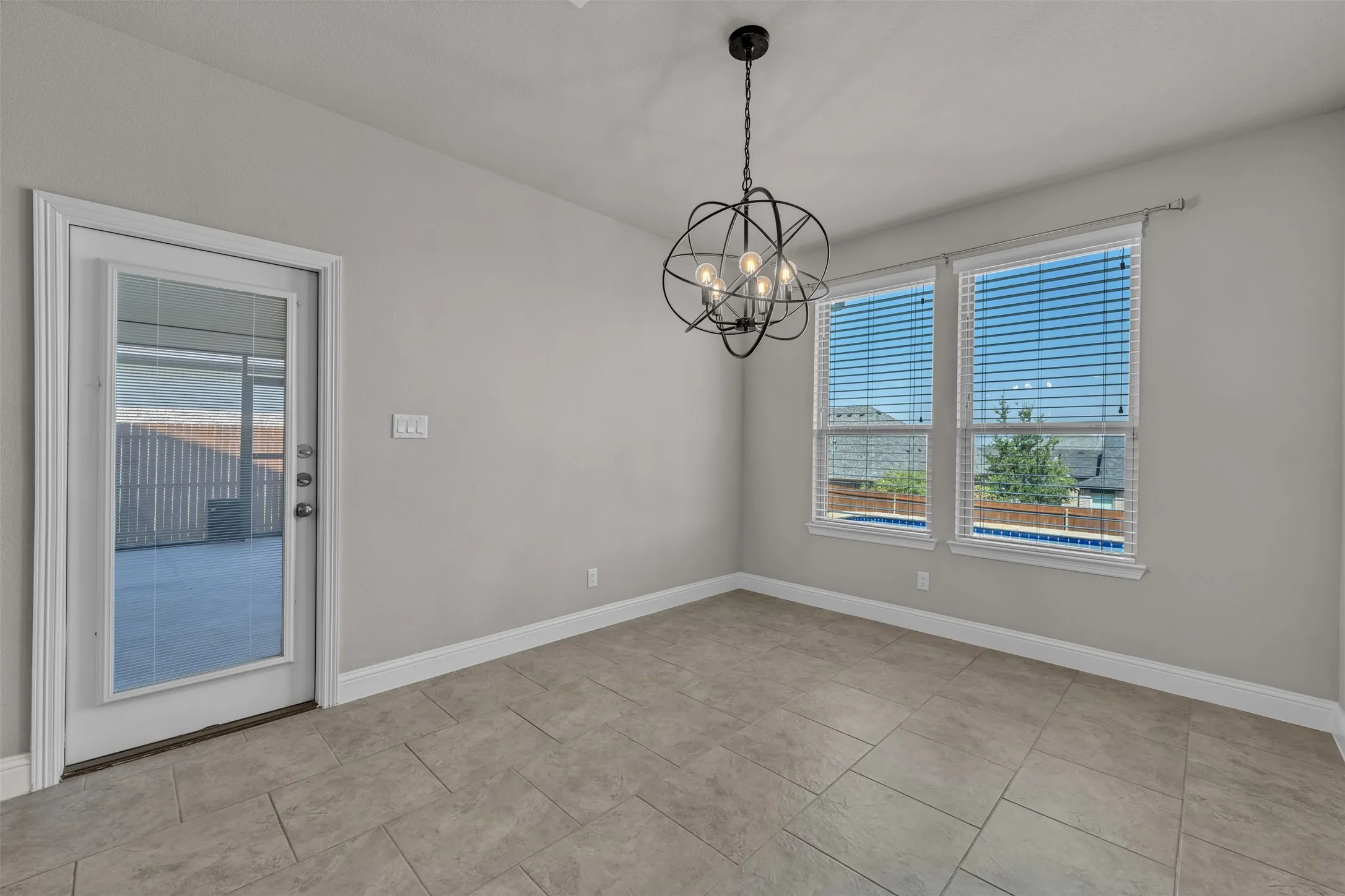 Recessed lighting, contemporary black chandelier, tile flooring, two windows, and a glass-paneled door