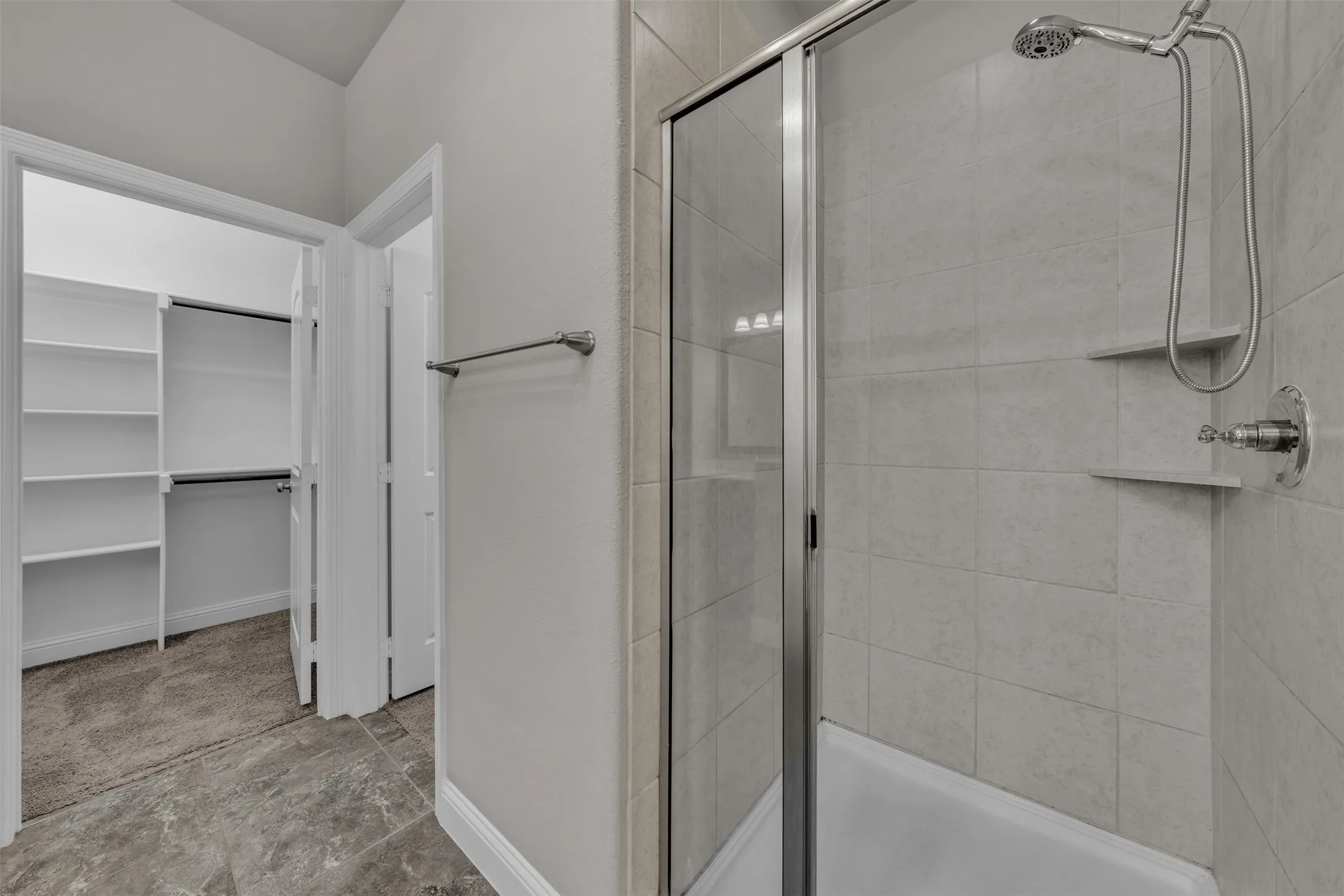 Walk-in shower with a glass enclosure, tiled walls, and built-in shelving