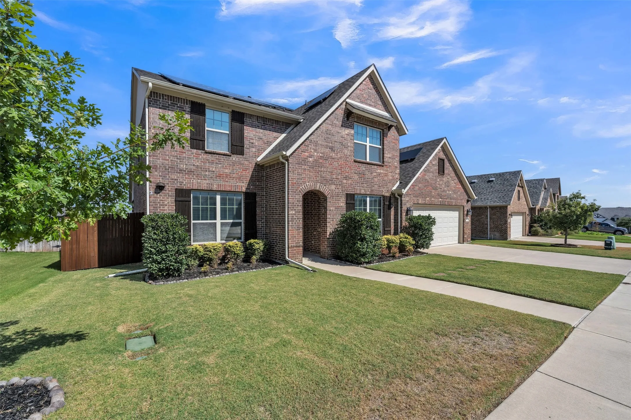 Brick exterior with dark shutters, gabled rooflines, and a two-car garage