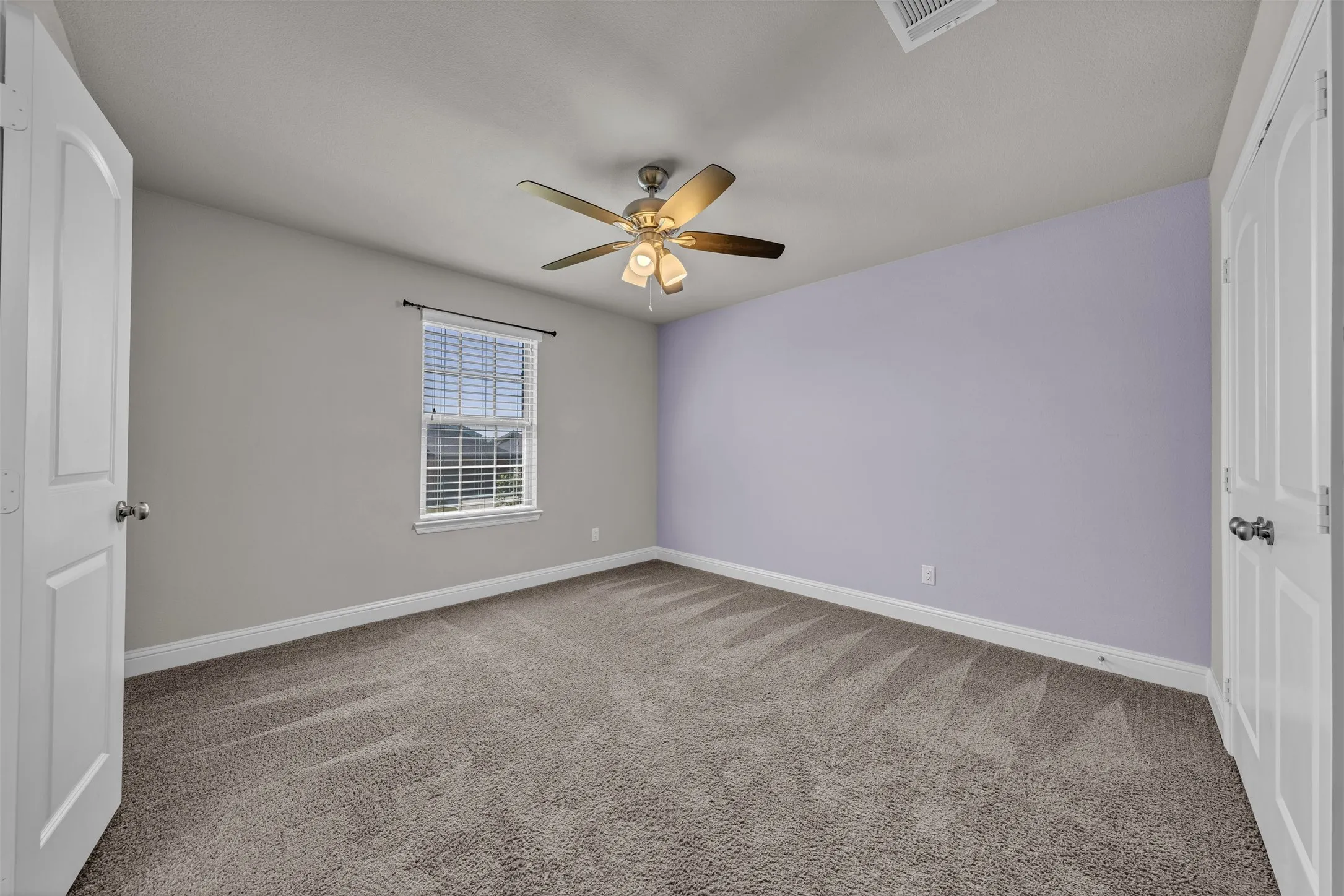 Carpeted room featuring a ceiling fan with integrated lighting, a window with blinds, and white interior doors
