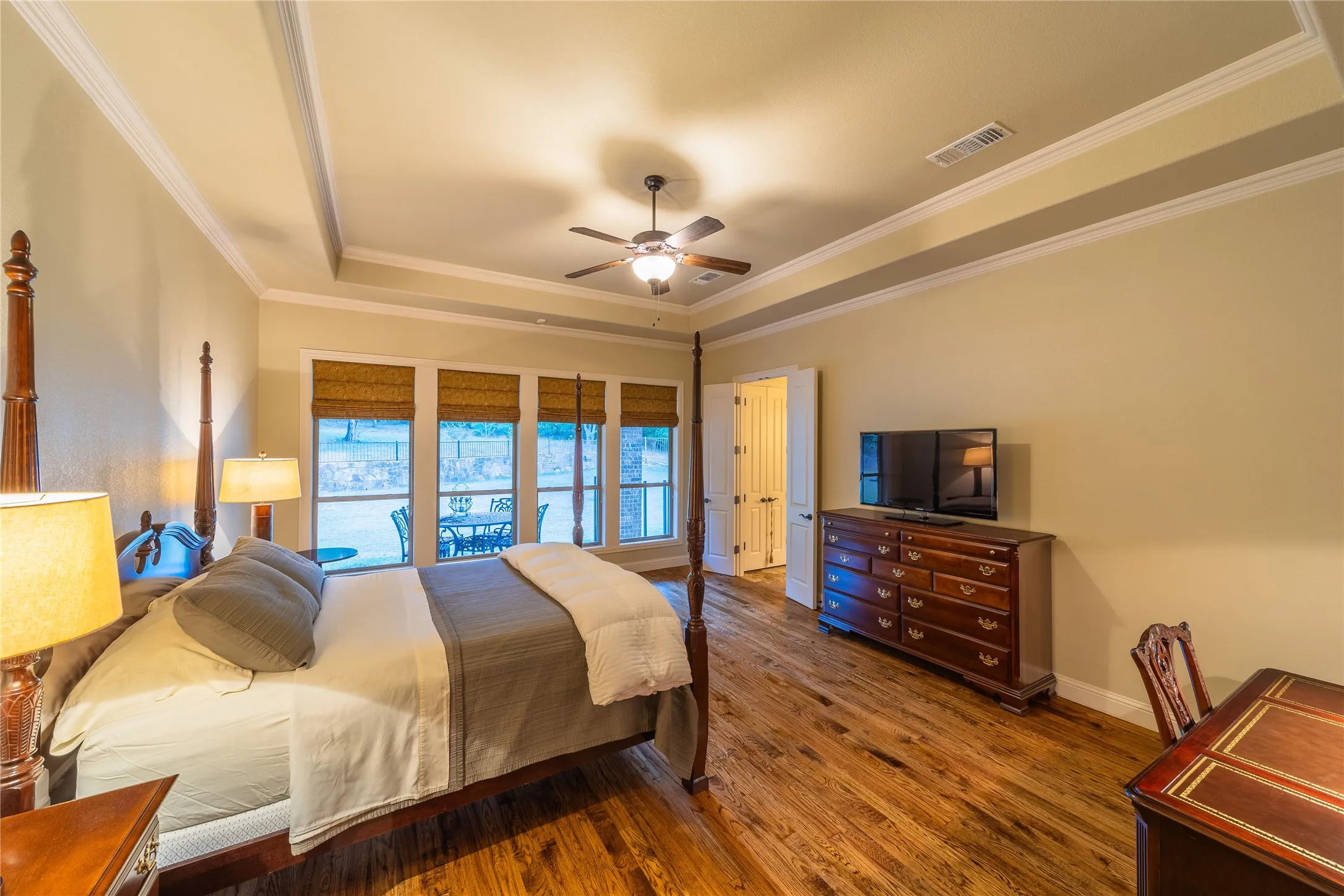 The primary bedroom has views to the back yard through the covered patio which blocks the harsh summer sun. The door in the center of the photo leads to the primary bathroom.