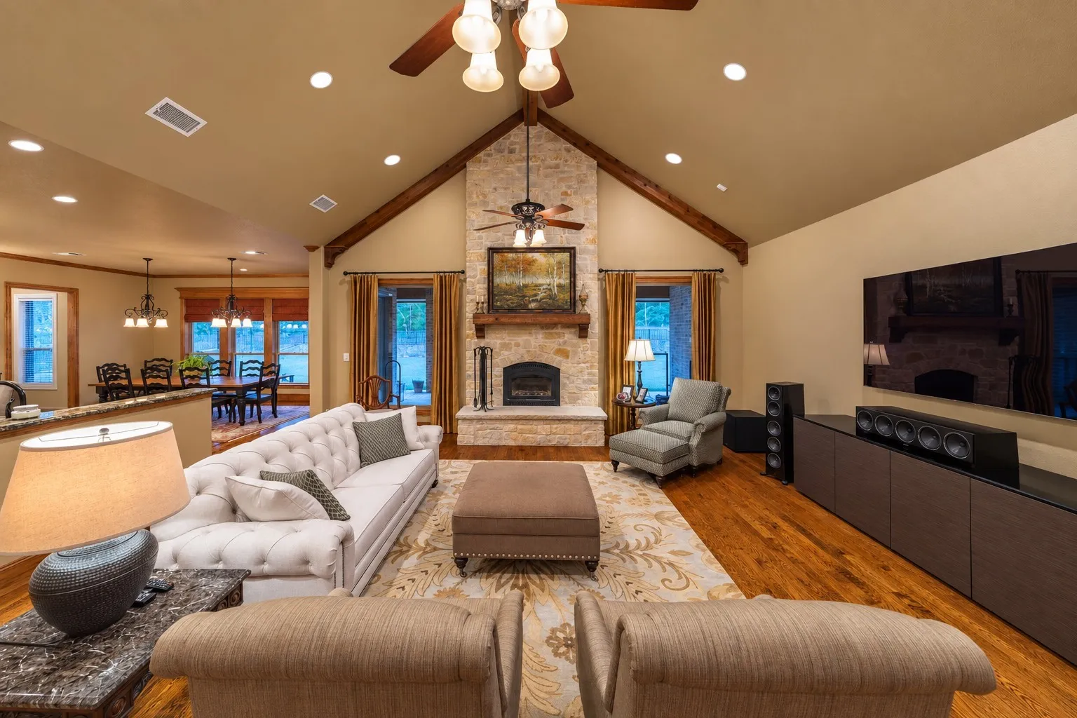 The living room features vaulted ceilings anchored by a wood burning fireplace.
