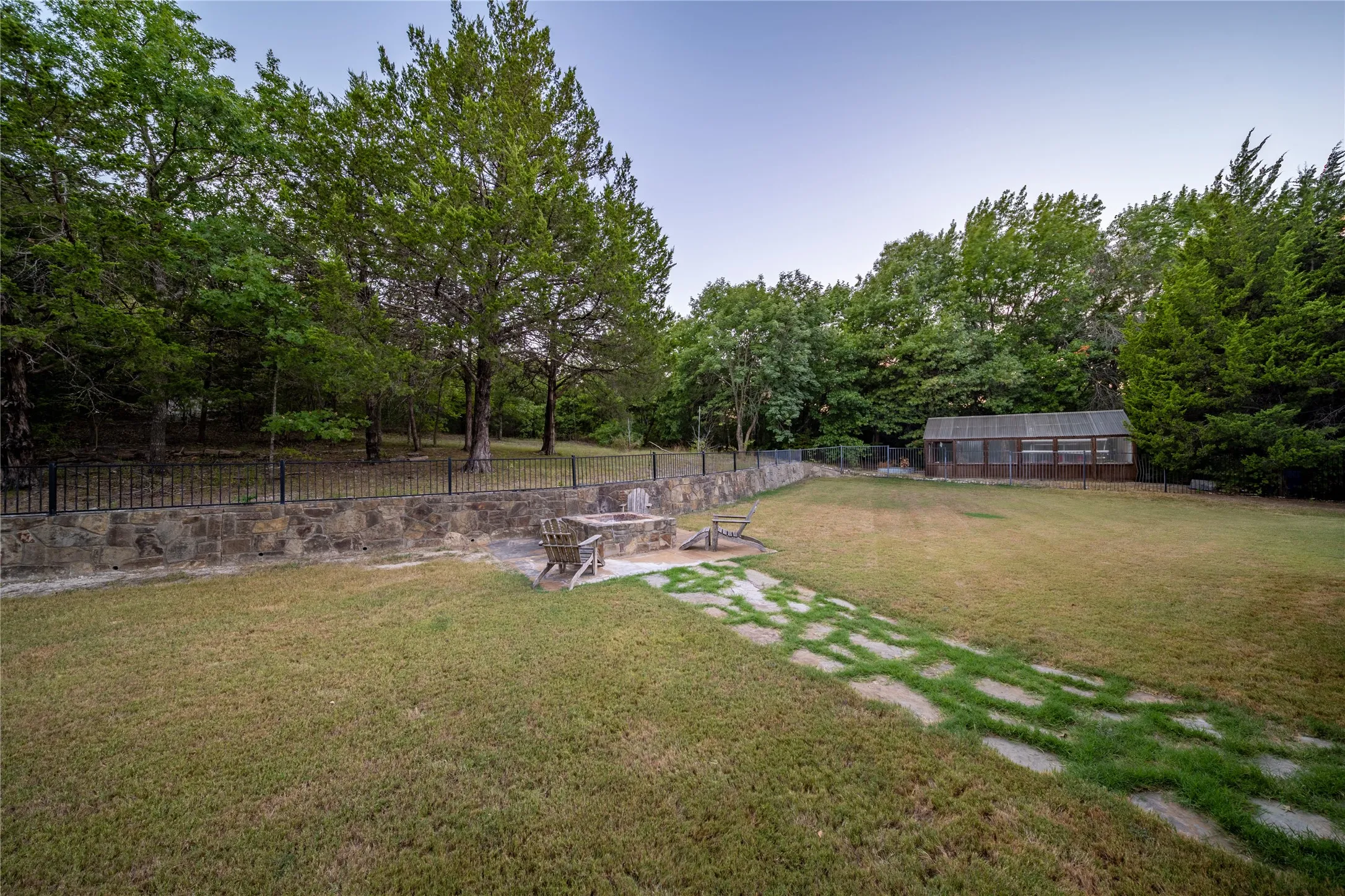 The back yard is separated from the upper back yard with a stone retaining wall.  The structure in the distance is the green house.