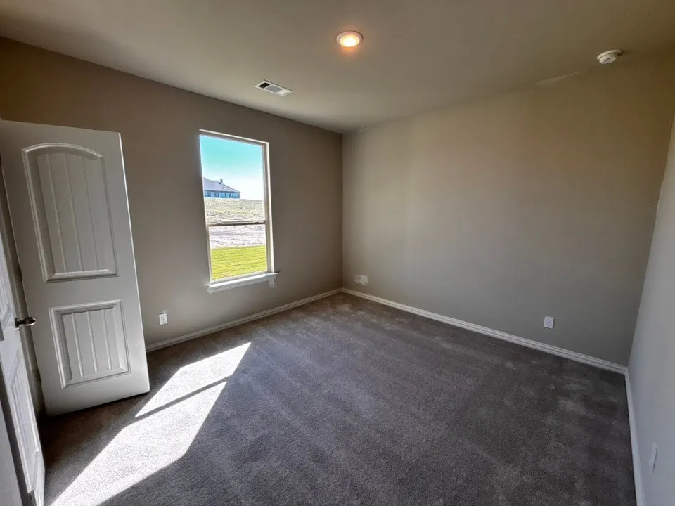 Neutral wall color, carpeted flooring, white trim, recessed lighting, and a paneled door