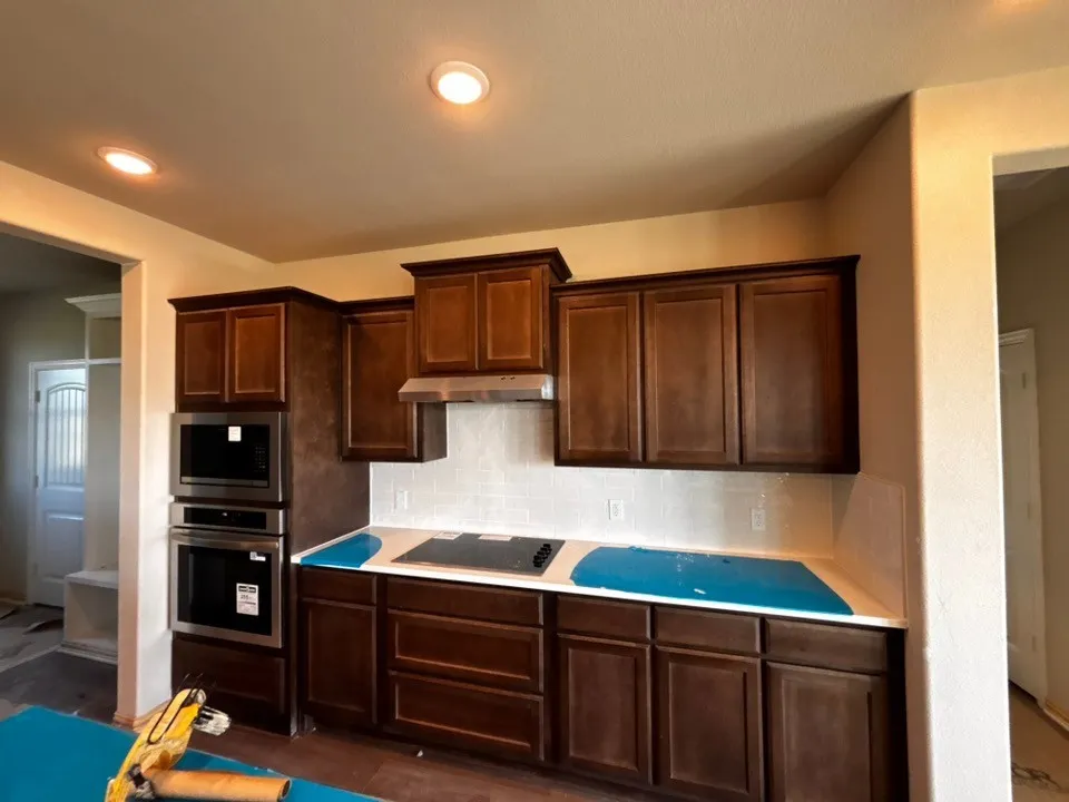 Kitchen featuring rich wood cabinetry, stainless steel appliances, a built-in oven and microwave, and a tile backsplash