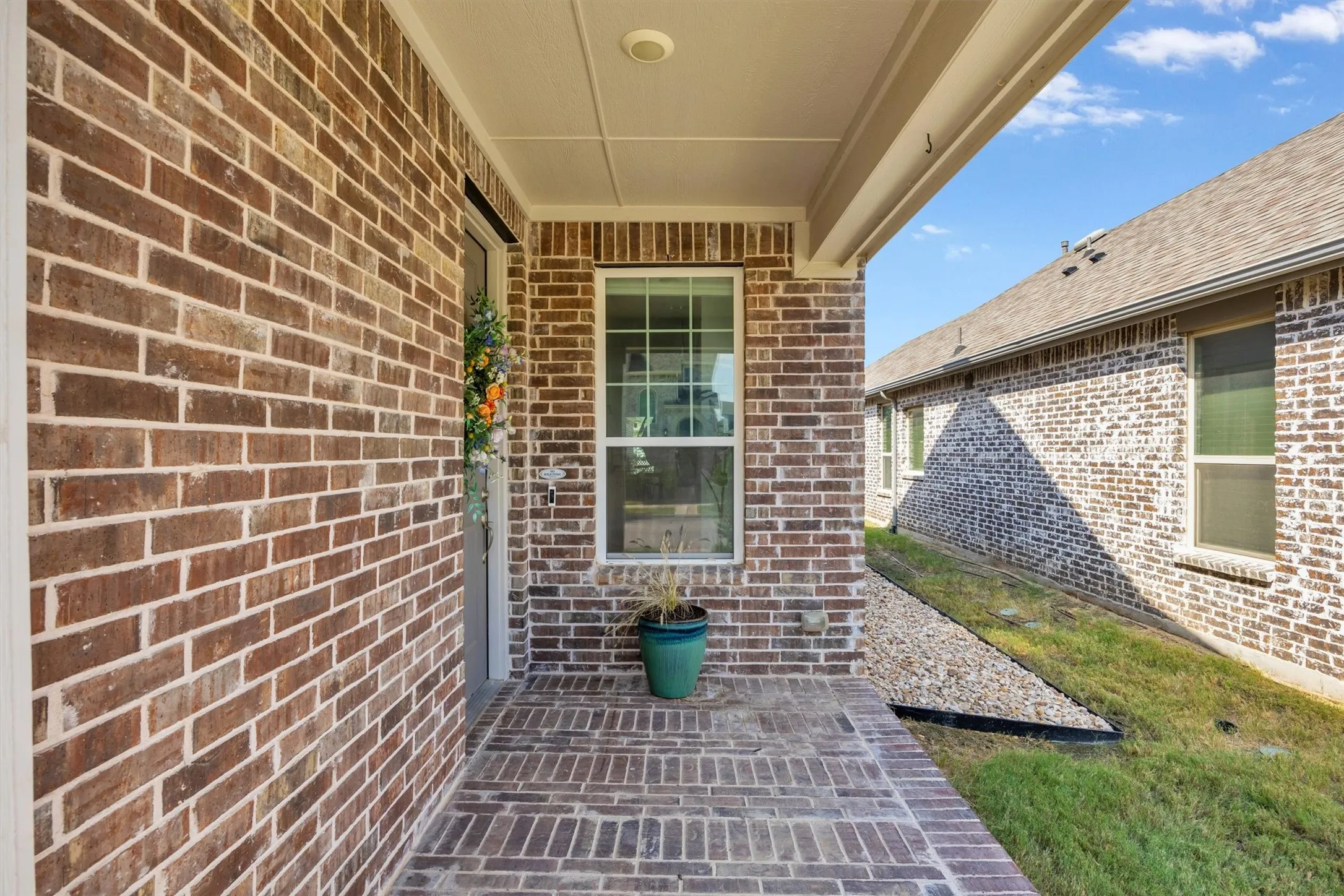 Brick exterior with a covered porch, brick pavers, and a single window