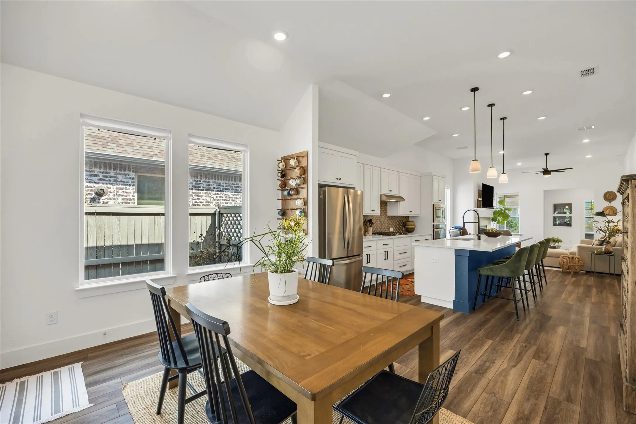 Vaulted ceilings, wood-finish flooring, recessed lighting, white cabinetry, and a kitchen island with pendant lighting