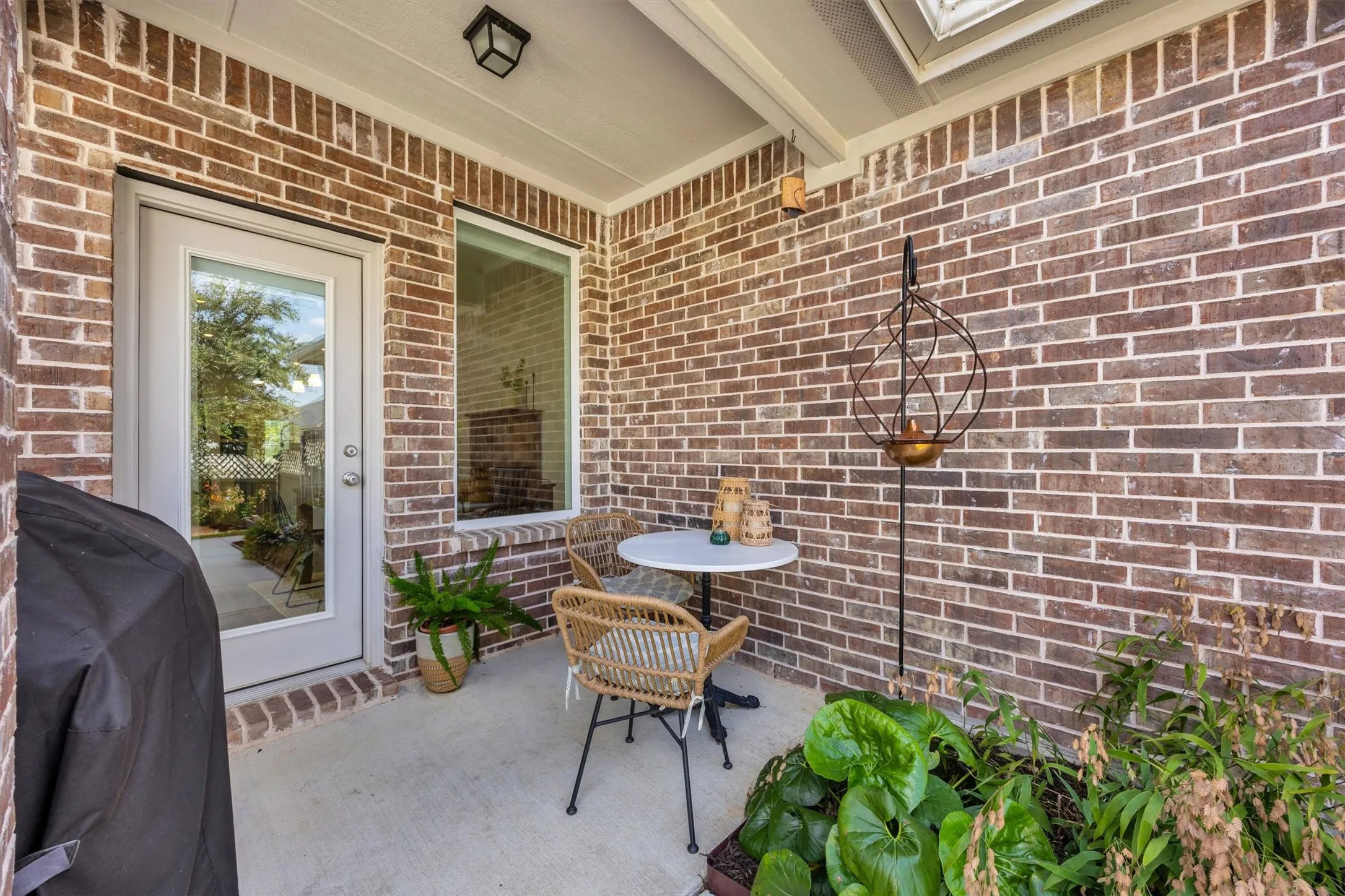 Covered outdoor patio with brick exterior walls, a concrete floor, and a full-light glass-paneled door