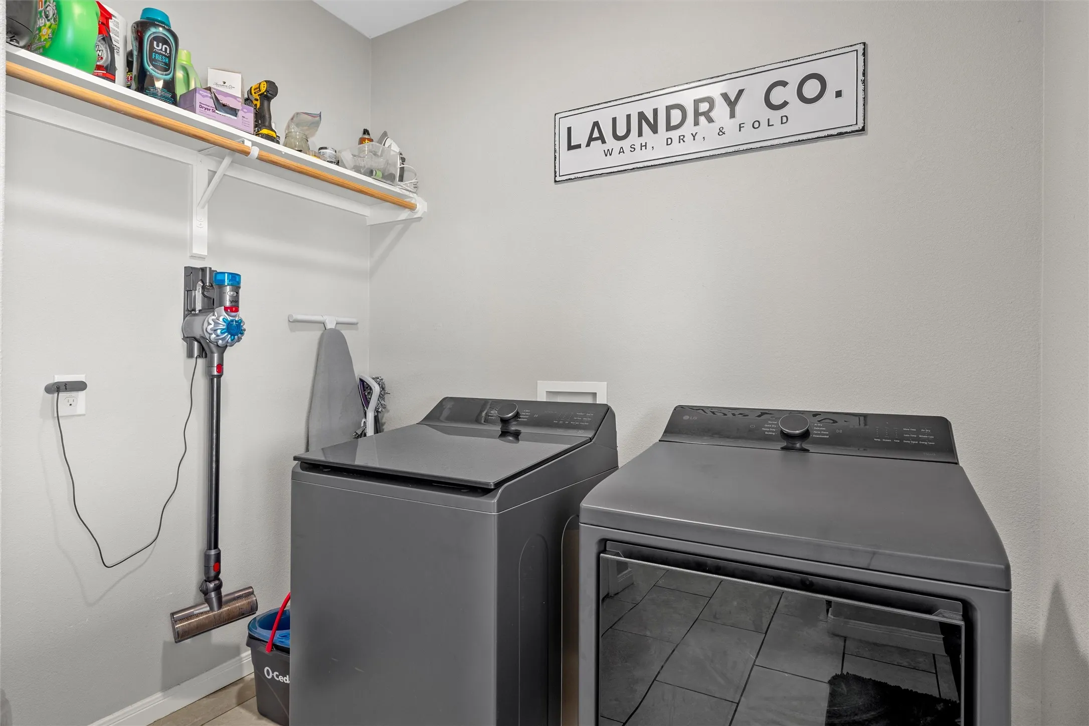 Dedicated laundry area featuring a wall-mounted shelf, hanging rod, and light gray walls