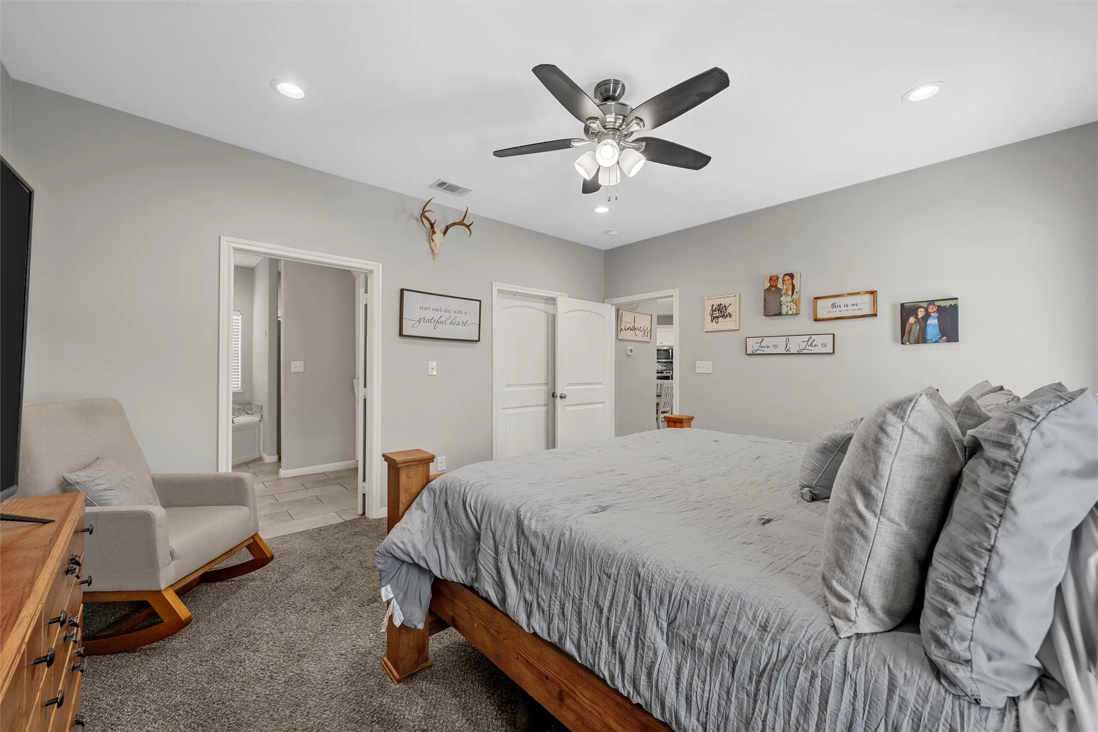 Neutral wall paint, recessed lighting, ceiling fan with light fixture, carpeted flooring, and a tiled bathroom entryway