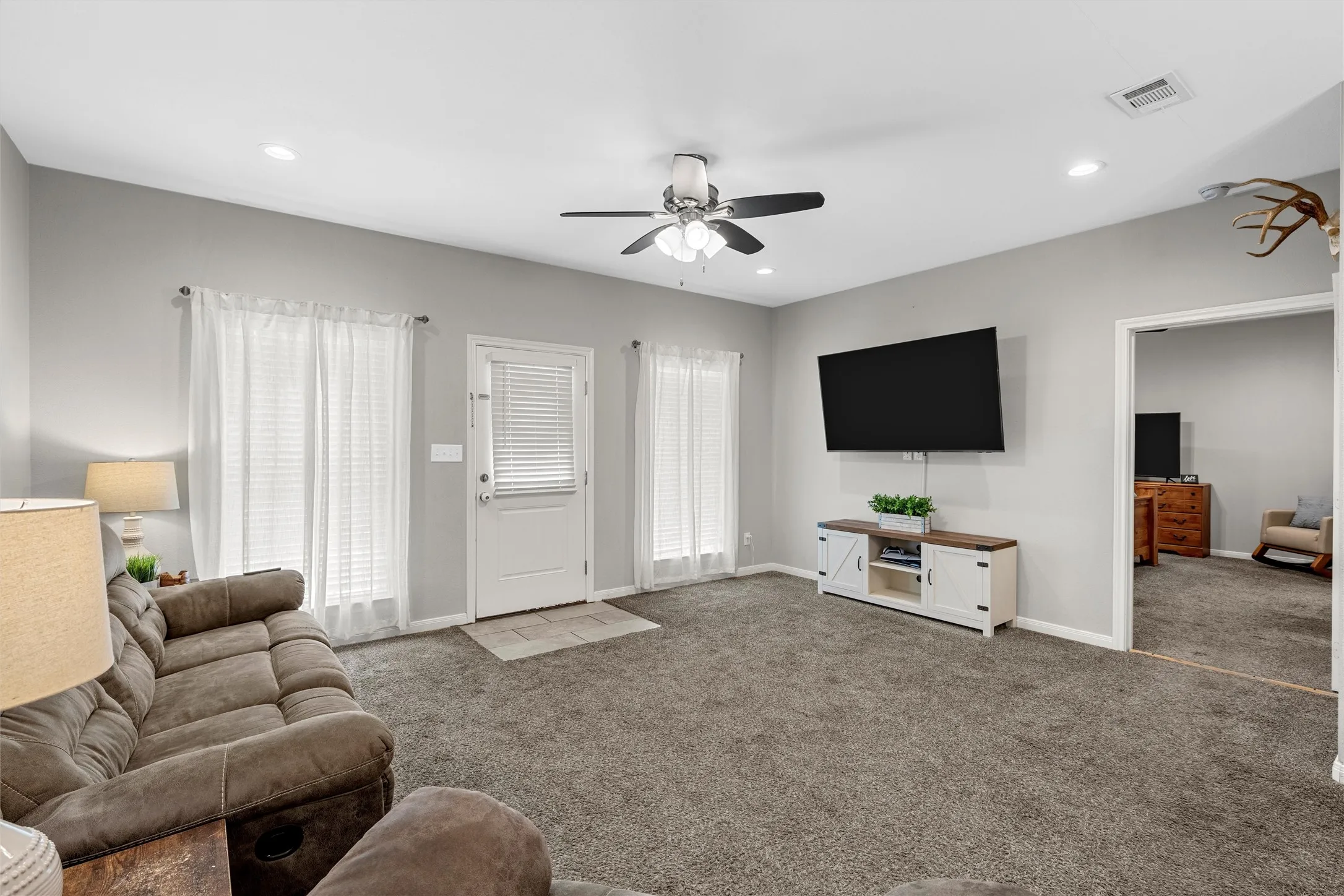 Carpeted living area with light gray walls, recessed lighting, and a ceiling fan