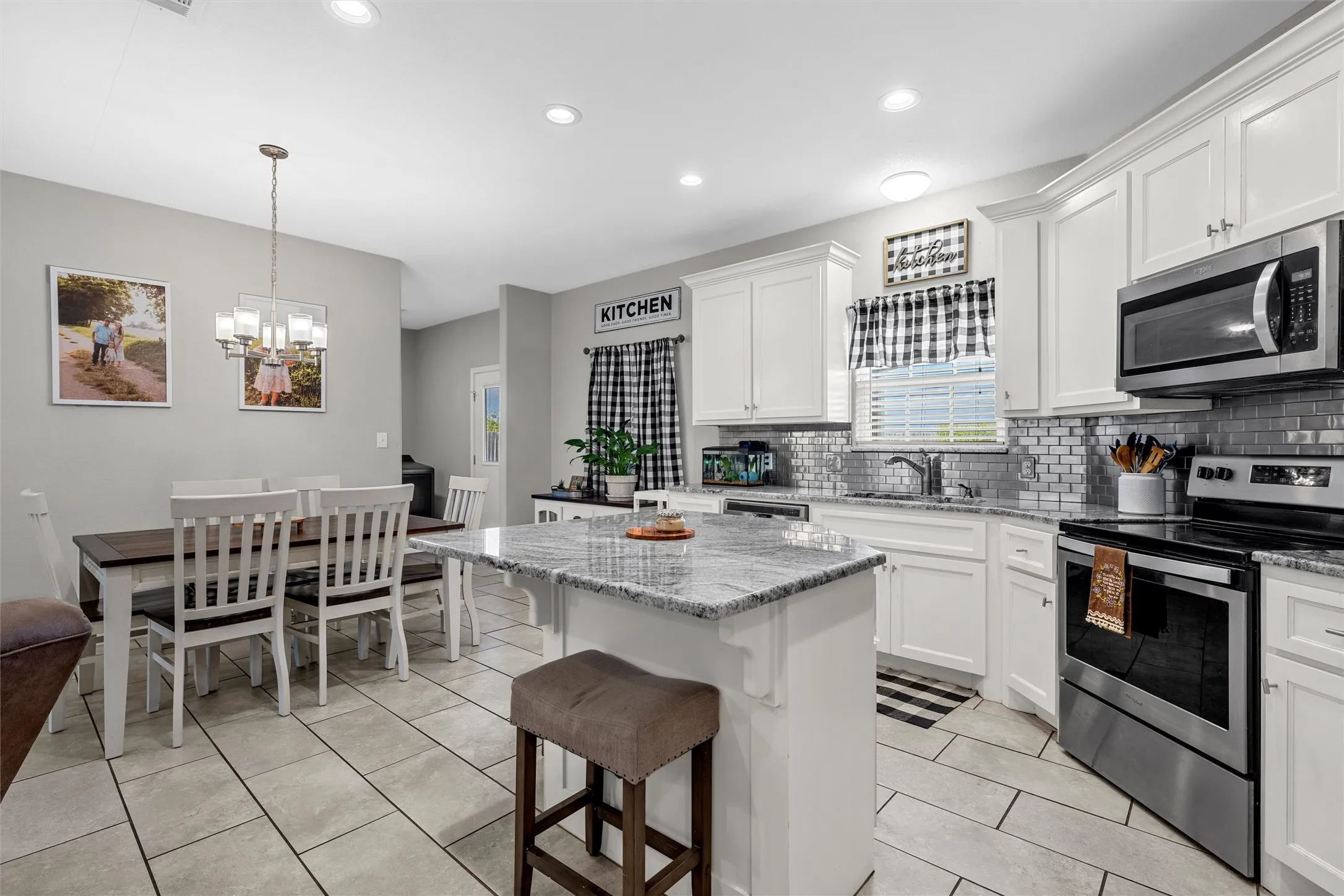 White cabinetry, granite countertops, tile flooring, stainless steel appliances, and a tile backsplash