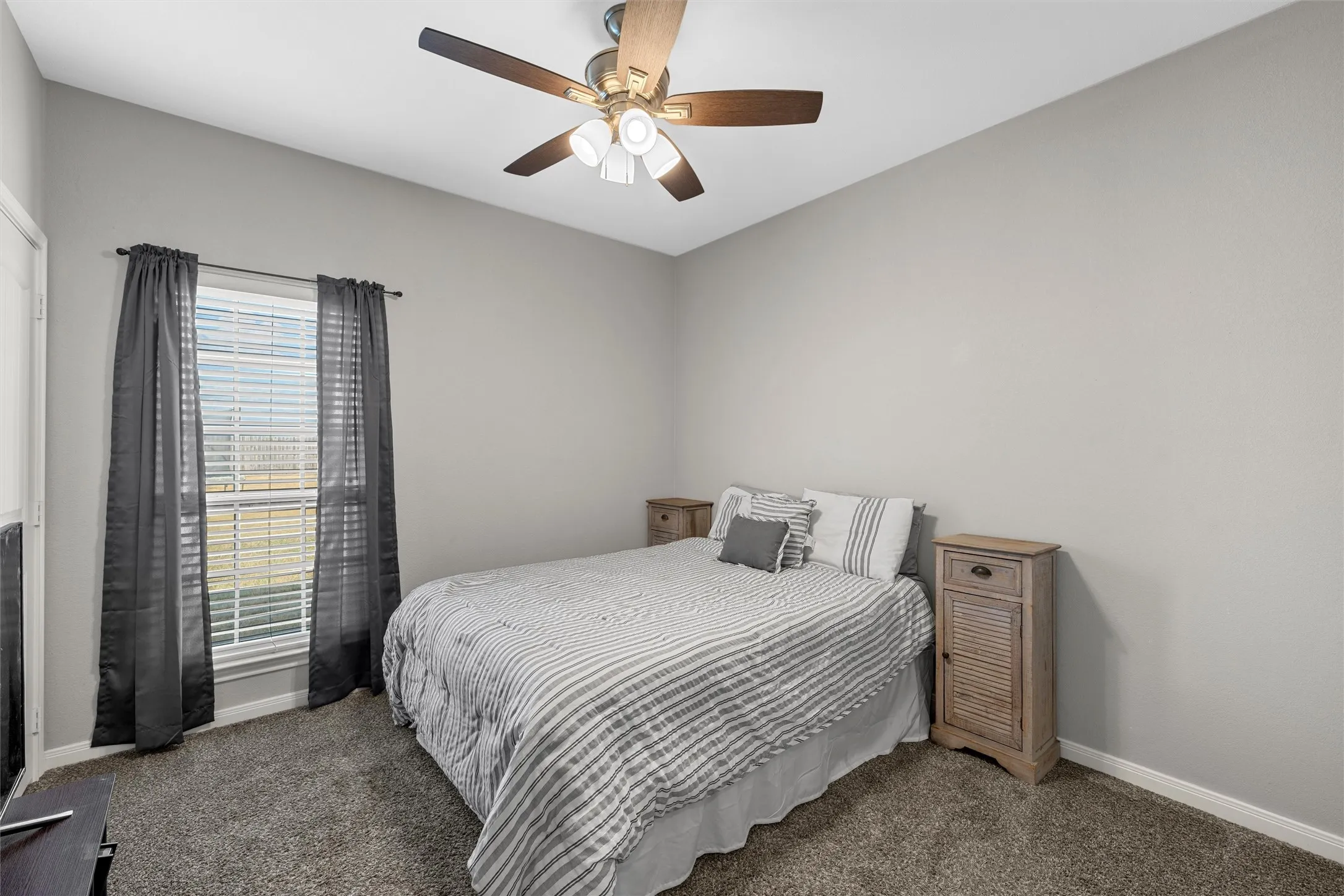 Vaulted ceiling with a ceiling fan, carpeted flooring, and a large window