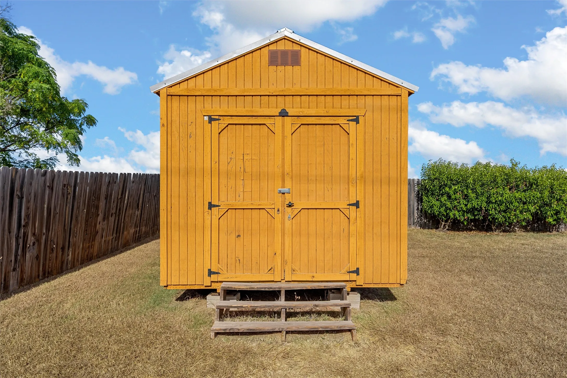 Freestanding shed with wood siding and a dual-door entry