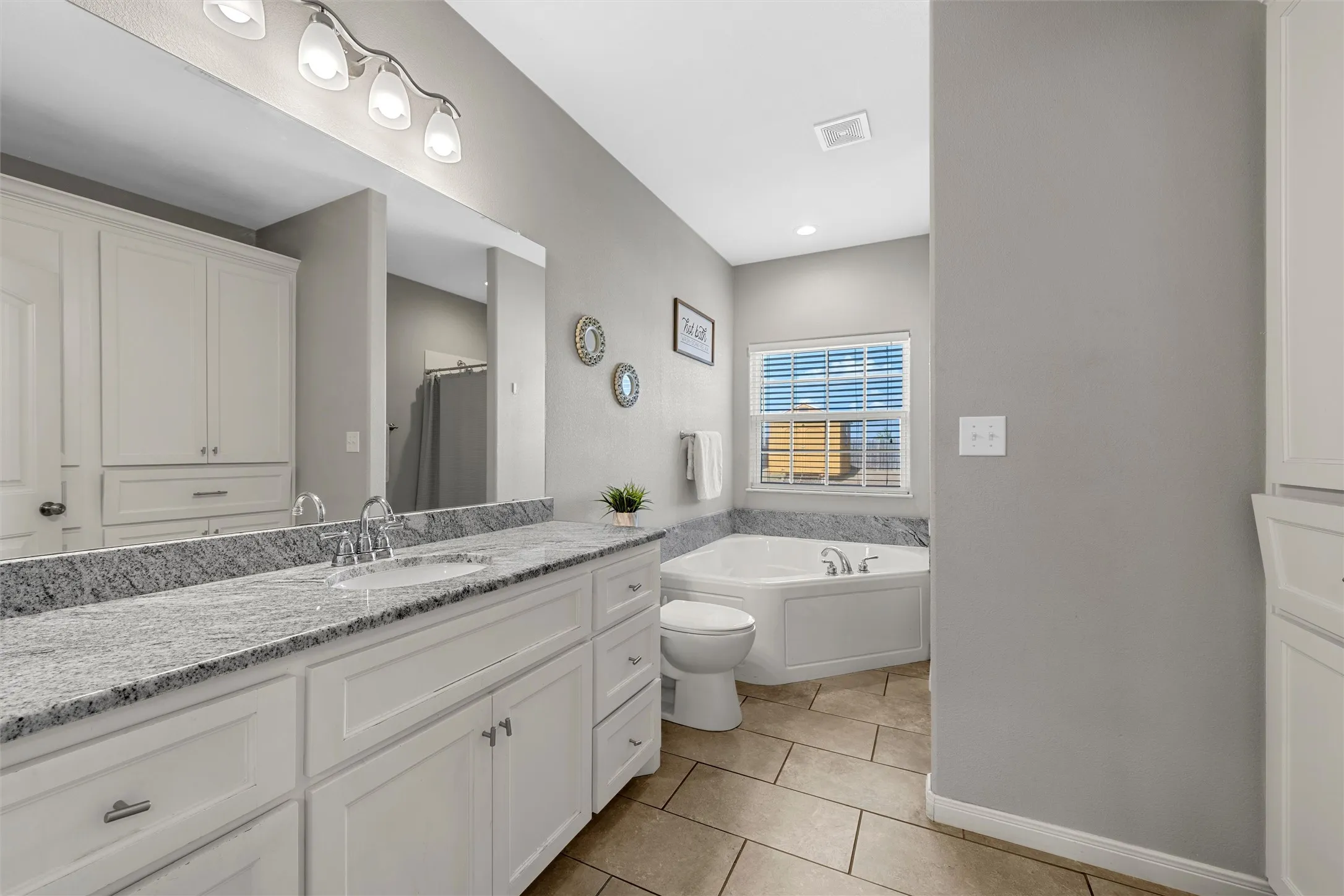 Dual vanity with stone-finish countertop, undermount sinks, and white cabinetry