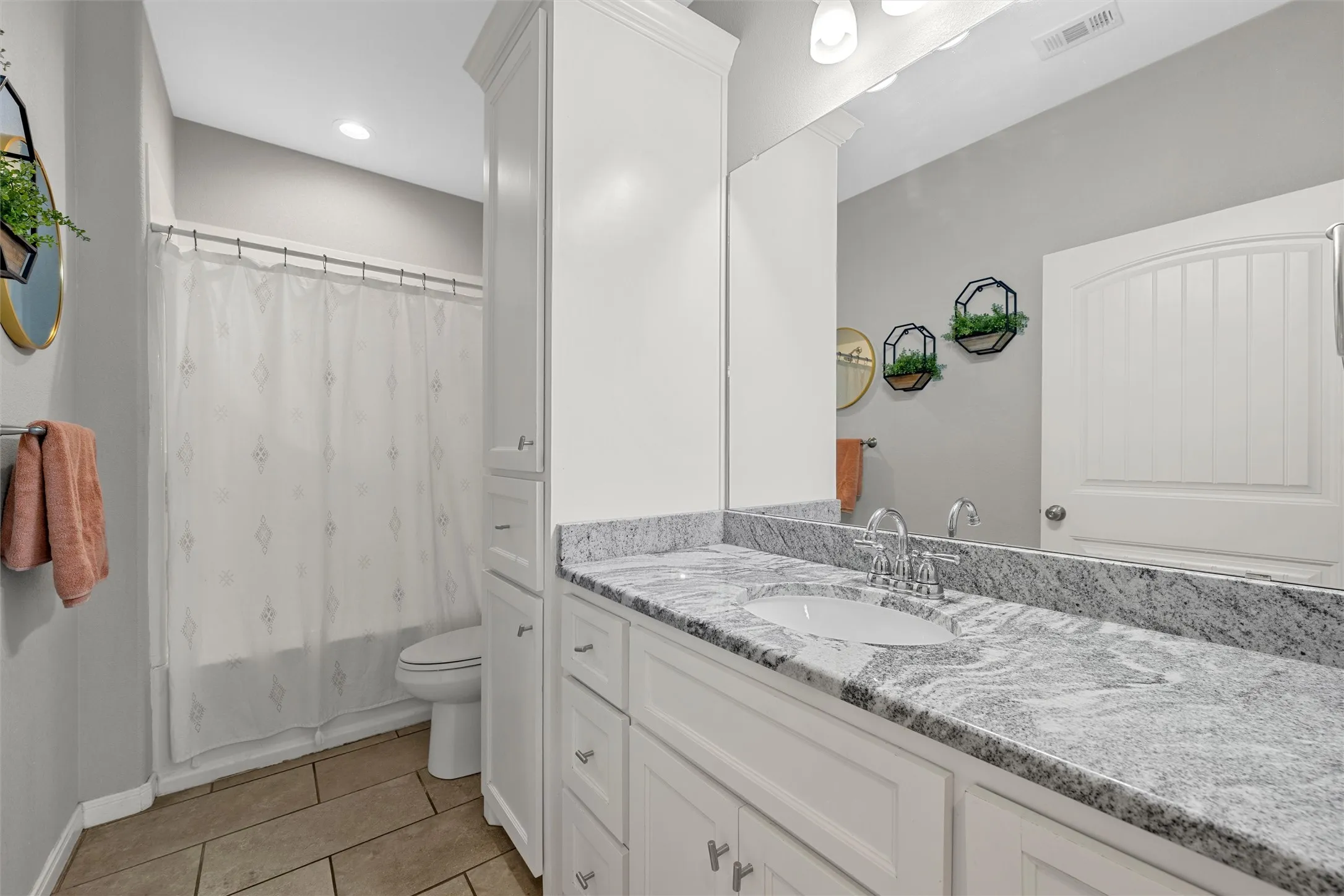 White vanity with dual sinks, a large mirror, and ample under-sink storage